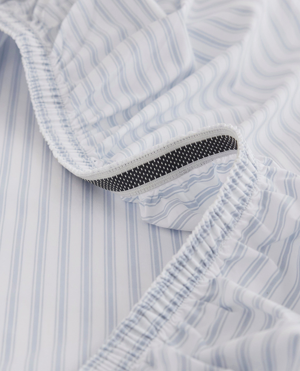 Image 2 of 6 showing Rise & Fall's Crisp & Cool organic cotton fitted bed sheet in blue stripe ticking.