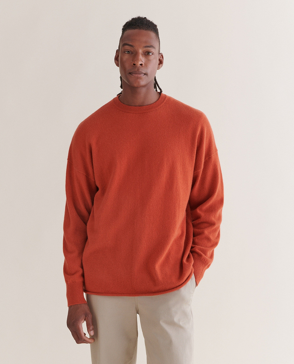 Image 3 of 4 showing man wearing Rise & Fall's rust coloured finest cashmere sweatshirt with beige trousers.
