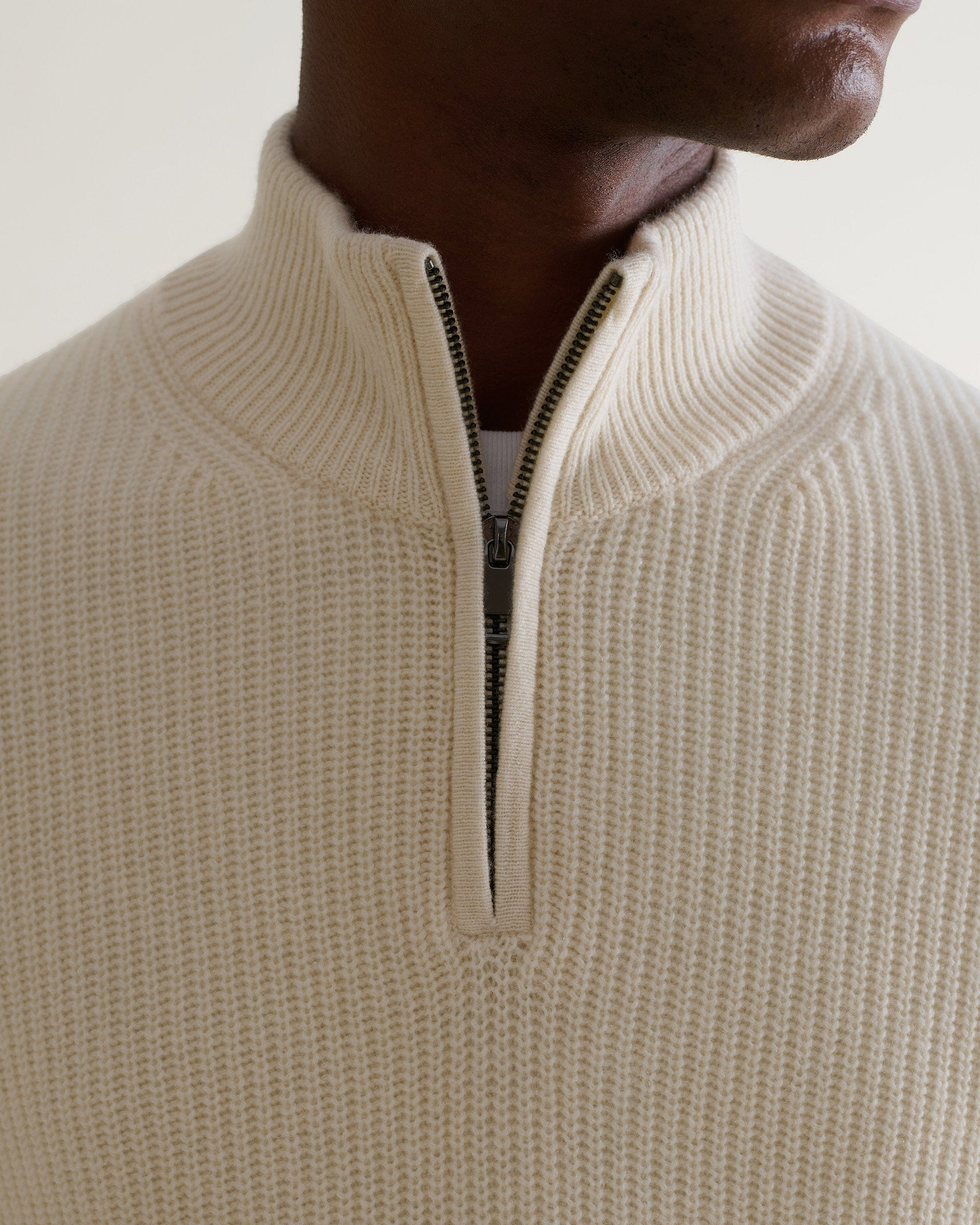 Image 4 of 6 showing close up of man wearing Rise & Fall's Cashmere Merino Fishermans Rib 1/4 Zip Jumper in cream.