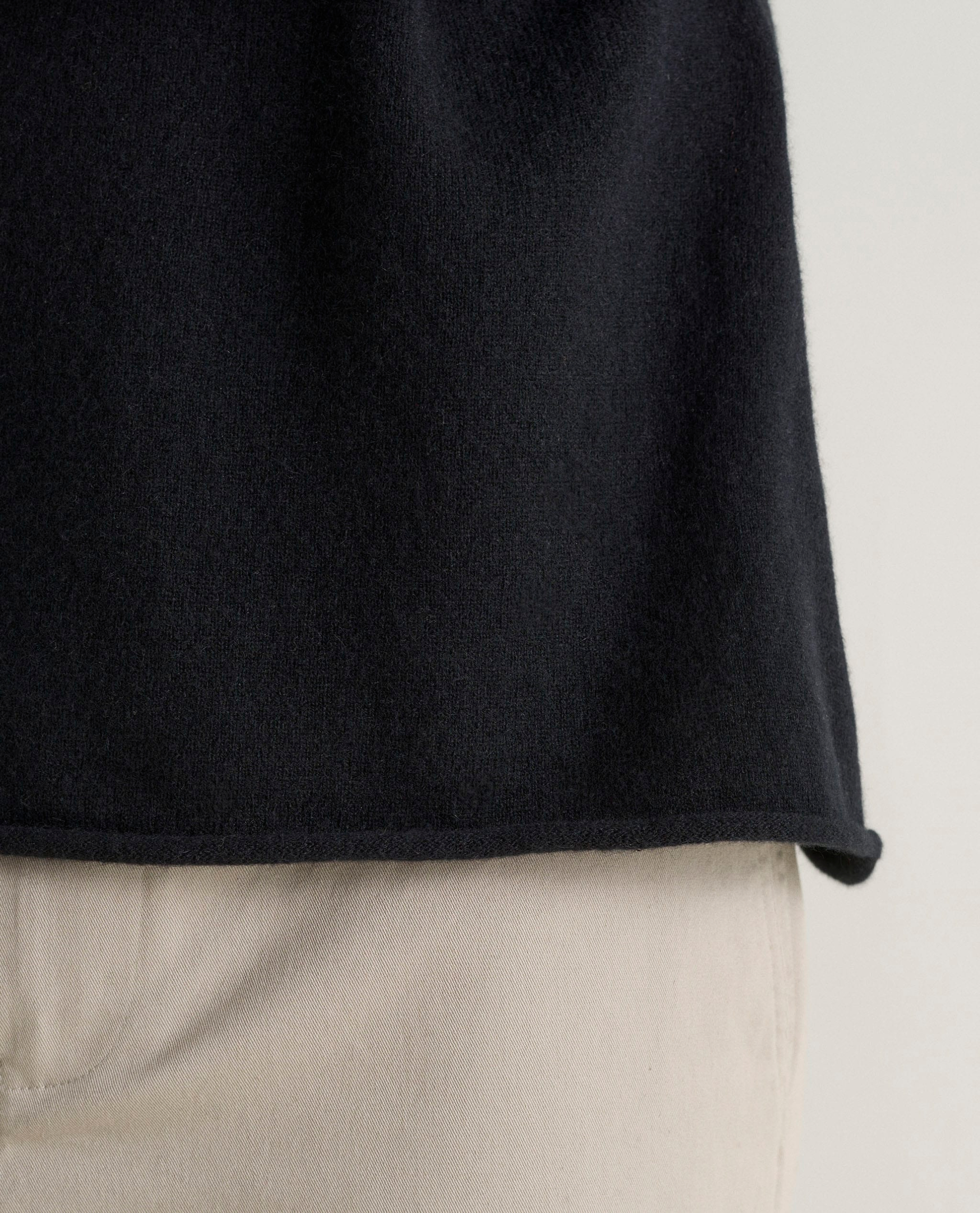 Image 5 of 5 showing close up of Rise & Fall's black finest cashmere sweatshirt with stone-coloured trousers.