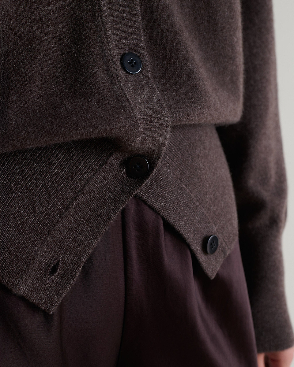 Image 5 of 5 showing close up of Rise & Fall's chocolate brown fine cashmere v-neck cardigan being worn with brown silk trousers.