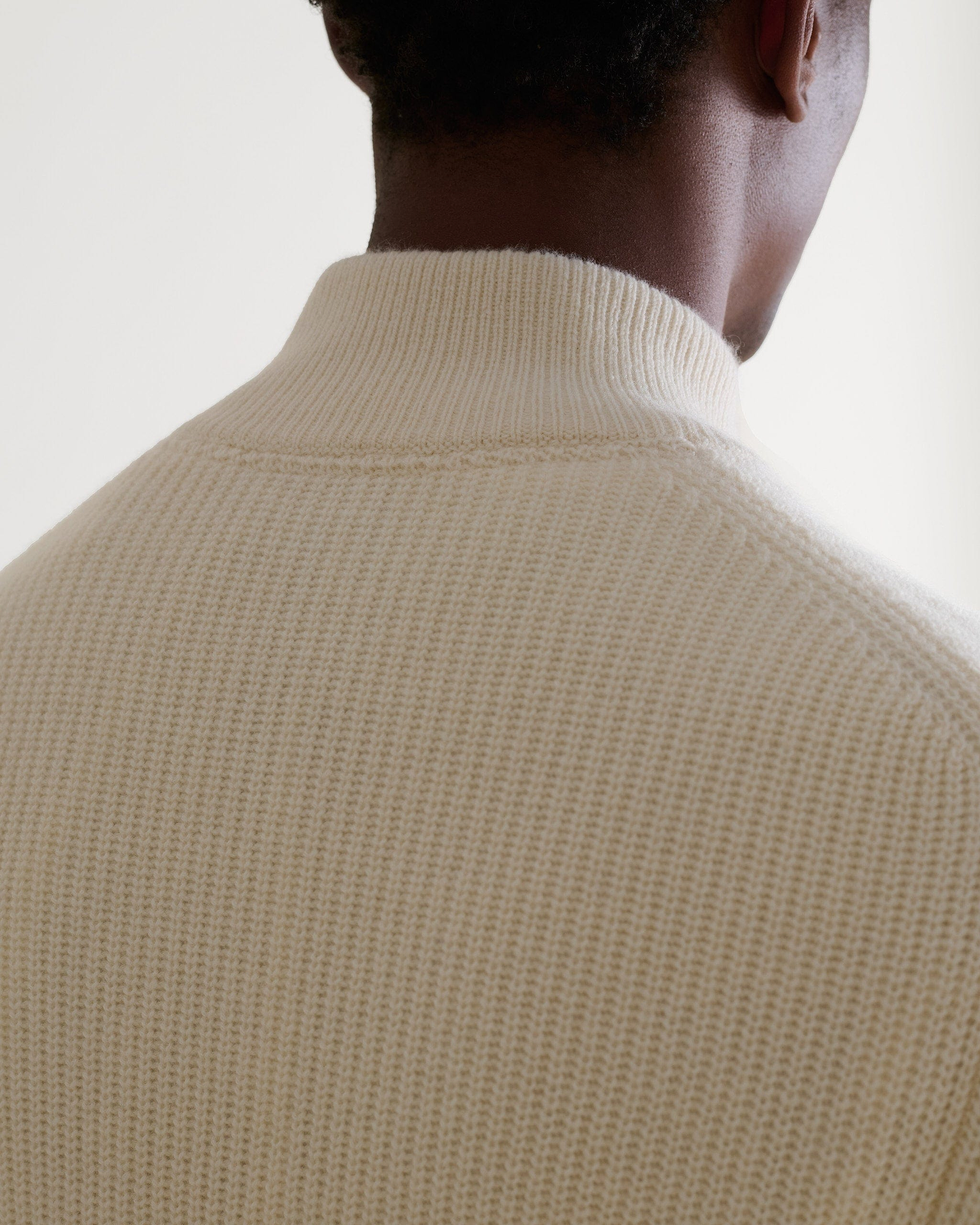 Image 5 of 6 showing close up man wearing Rise & Fall's Cashmere Merino Fishermans Rib 1/4 Zip Jumper in cream.