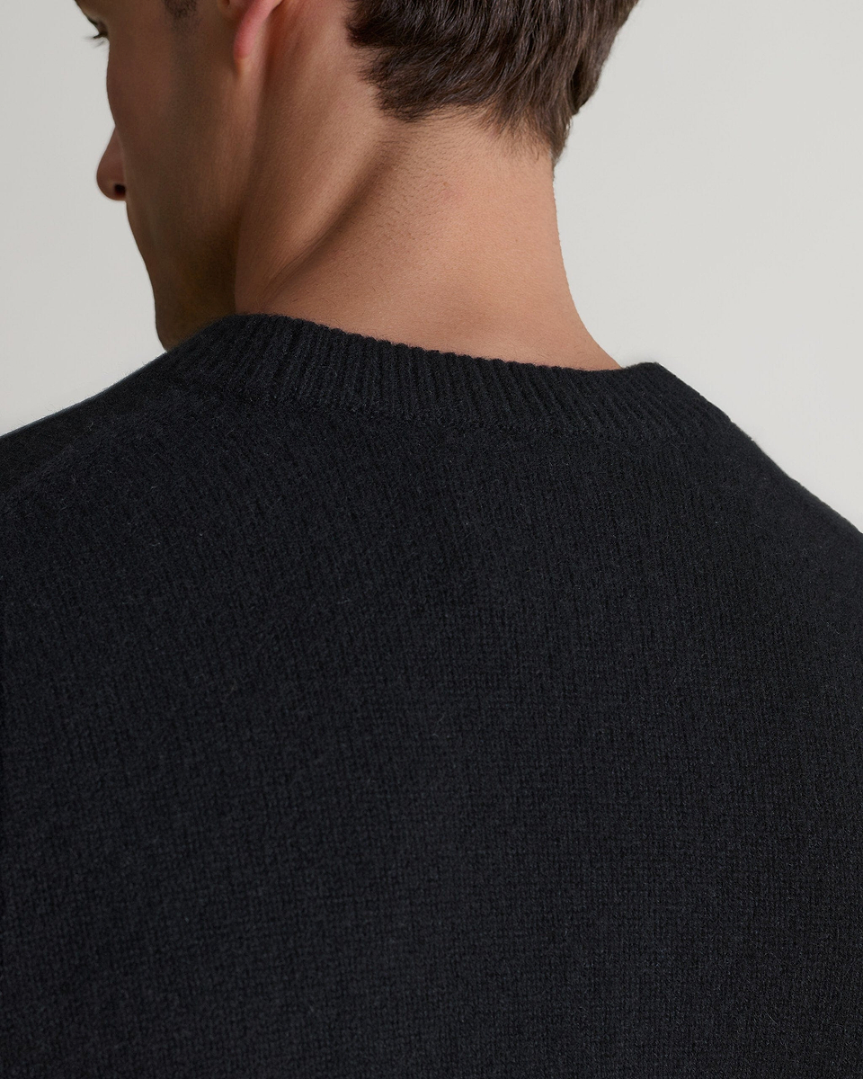 Image 5 of 7 showing close up of man wearing Rise & Fall's Finest Cashmere Mid-Weight Crew Neck Jumper in black.