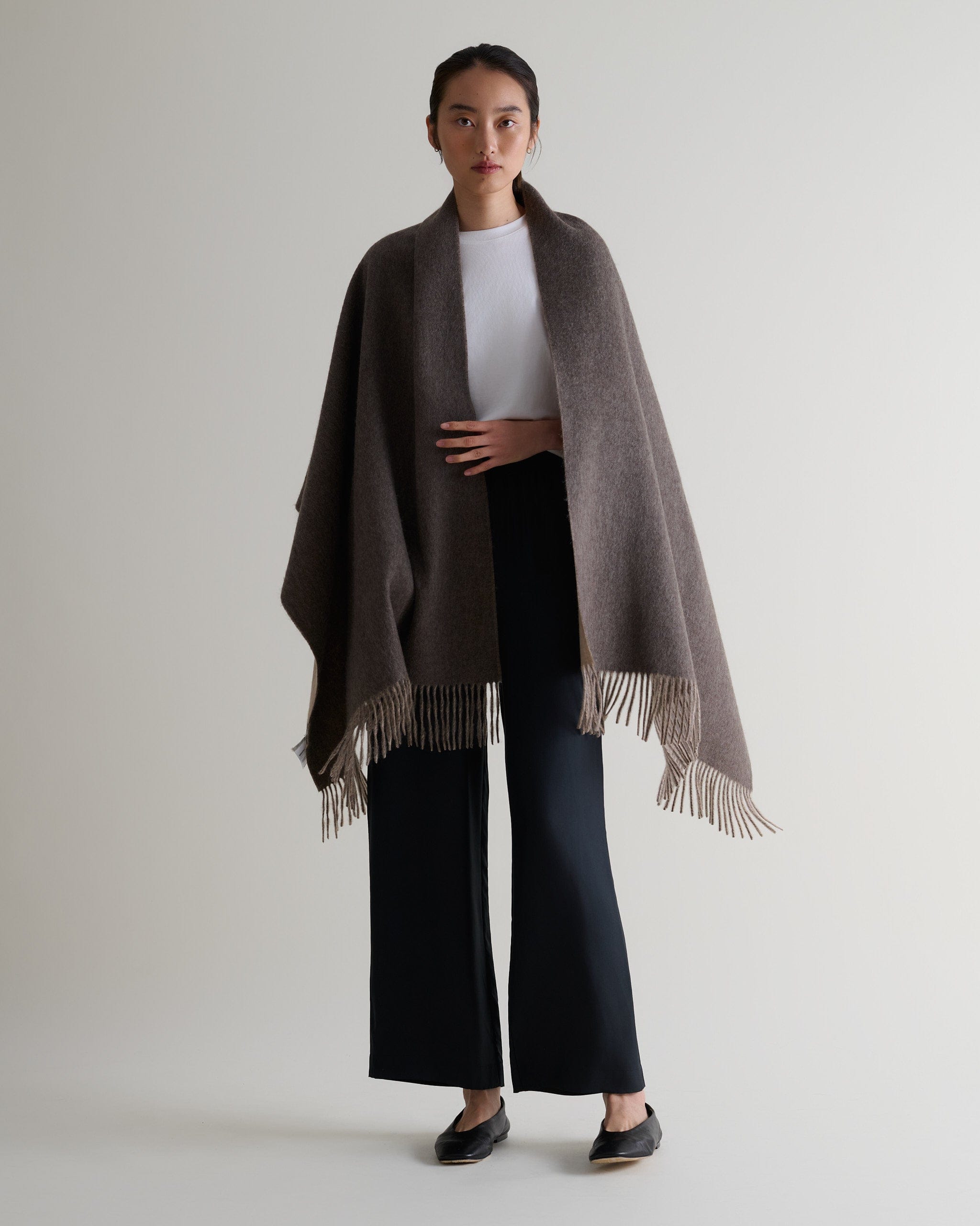 Image 6 of 7 showing woman wearing Rise & Fall's finest cashmere double faced wrap mole side with white T-shirt and black trousers.