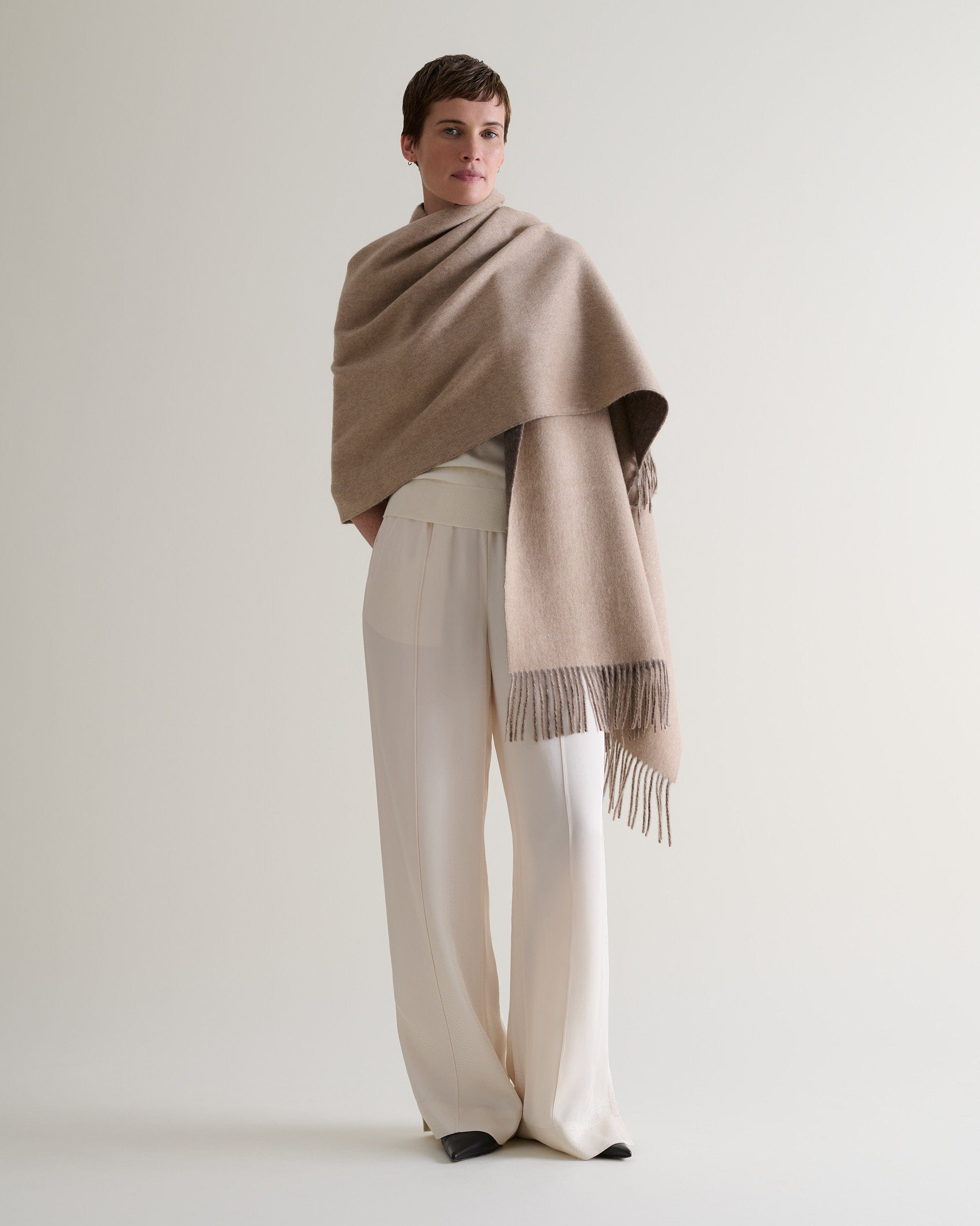 Image 7 of 7 showing woman wearing Rise & Fall's finest cashmere double faced wrap twine side with cream jumper and trousers.