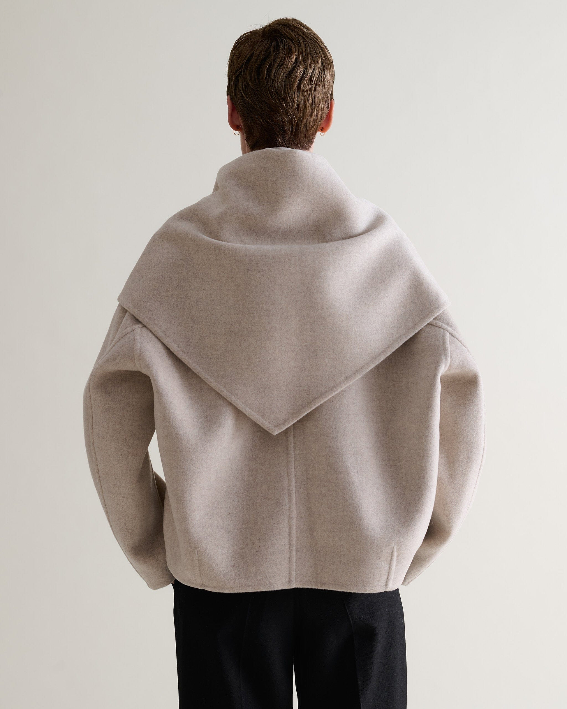 Image 9 of 9 showing back of woman wearing Rise & Fall's twine cashmere wool double faced scarf jacket with black trousers.