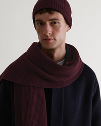Close up of man wearing Rise & Fall's oxblood cashmere merino ribbed scarf with matching coloured beanie and navy wool coat