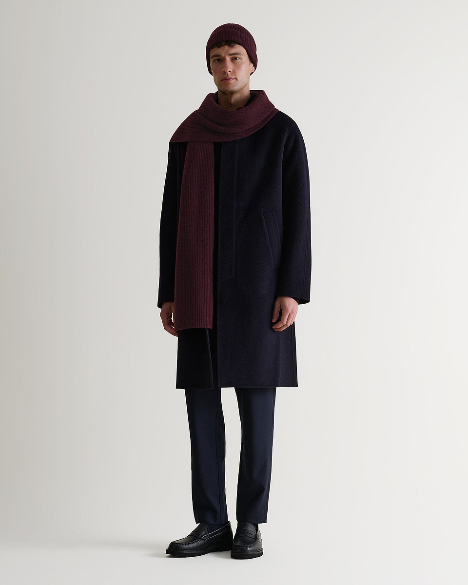 Full portrait view of man wearing Rise & Fall's oxblood cashmere merino ribbed scarf with matching coloured beanie and navy wool coat