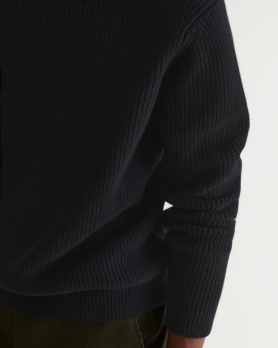 Close up of Rise & Fall's cashmere merino stand neck jumper in black.
