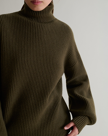 Close up of Rise & Fall's cashmere merino wool Ottoman ribbed roll neck jumper in military green.