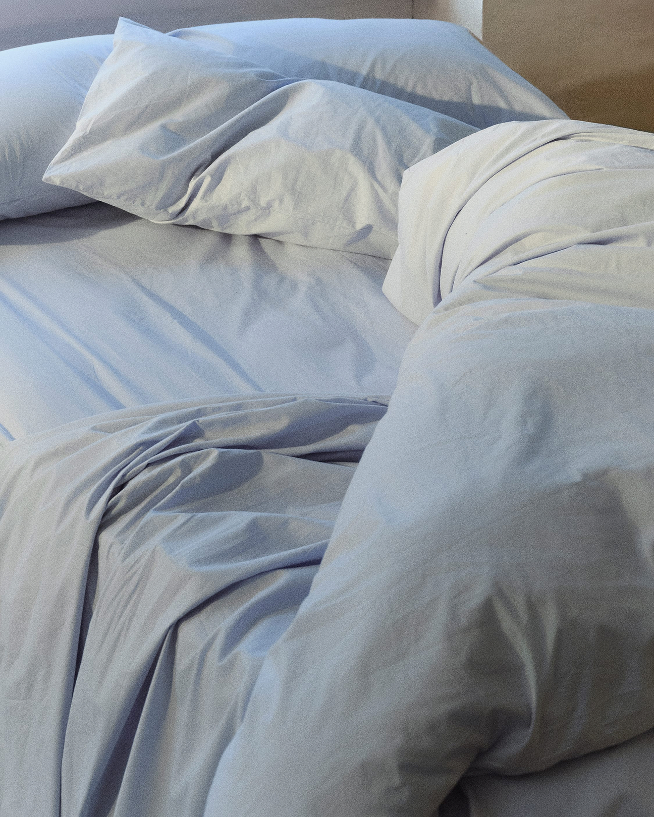 An unmade bed in light blue.