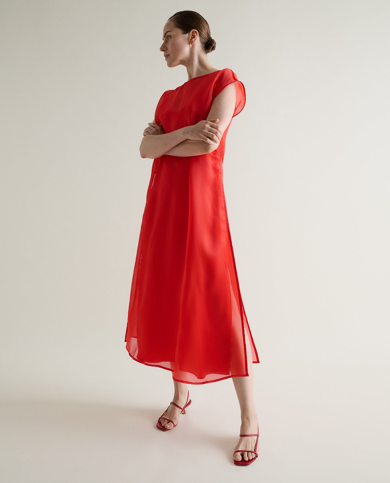 Woman wears Rise & Fall's red silk organza maxi dress. 