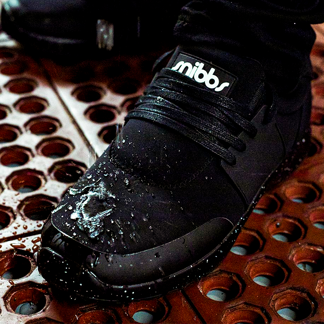 Black waterproof shoe with water droplets on a textured surface.