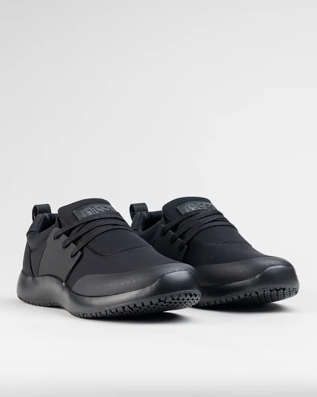 Black athletic shoes with elastic laces on a plain background.