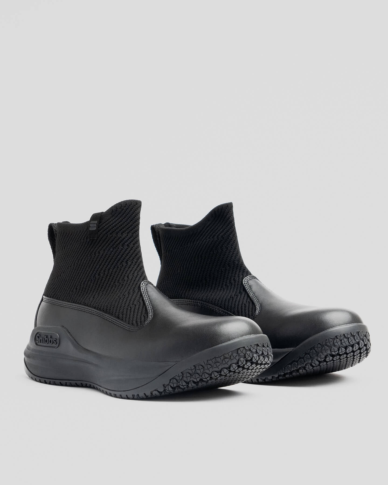 Pair of black ankle boots with textured soles on a gray background.