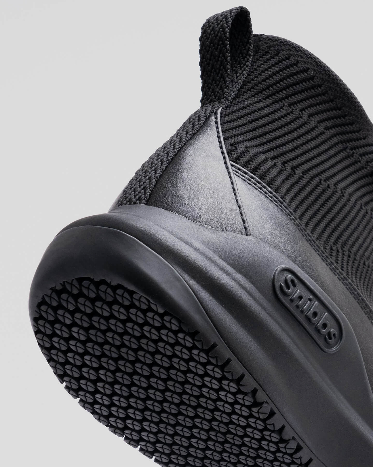 Close-up of a black shoe sole with textured grip and brand logo.