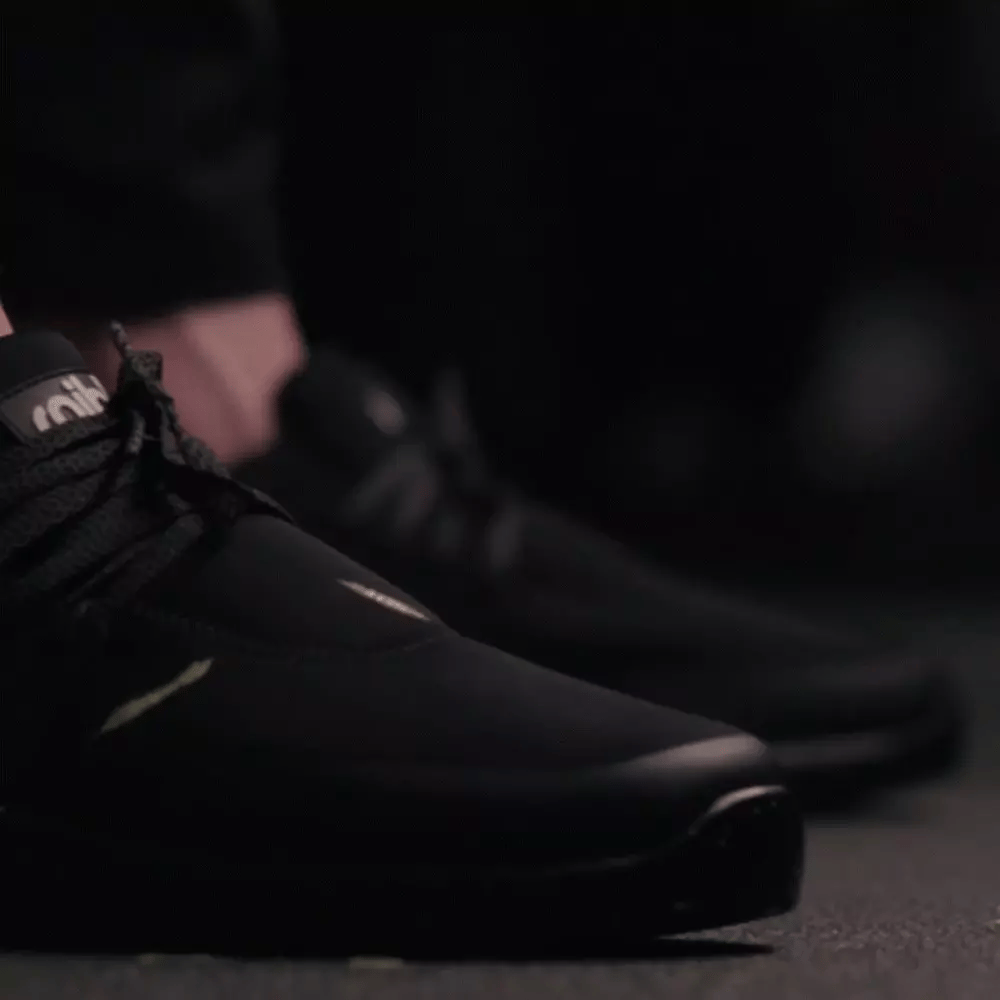 Close-up of a person's feet wearing black sports shoes on a dark background.