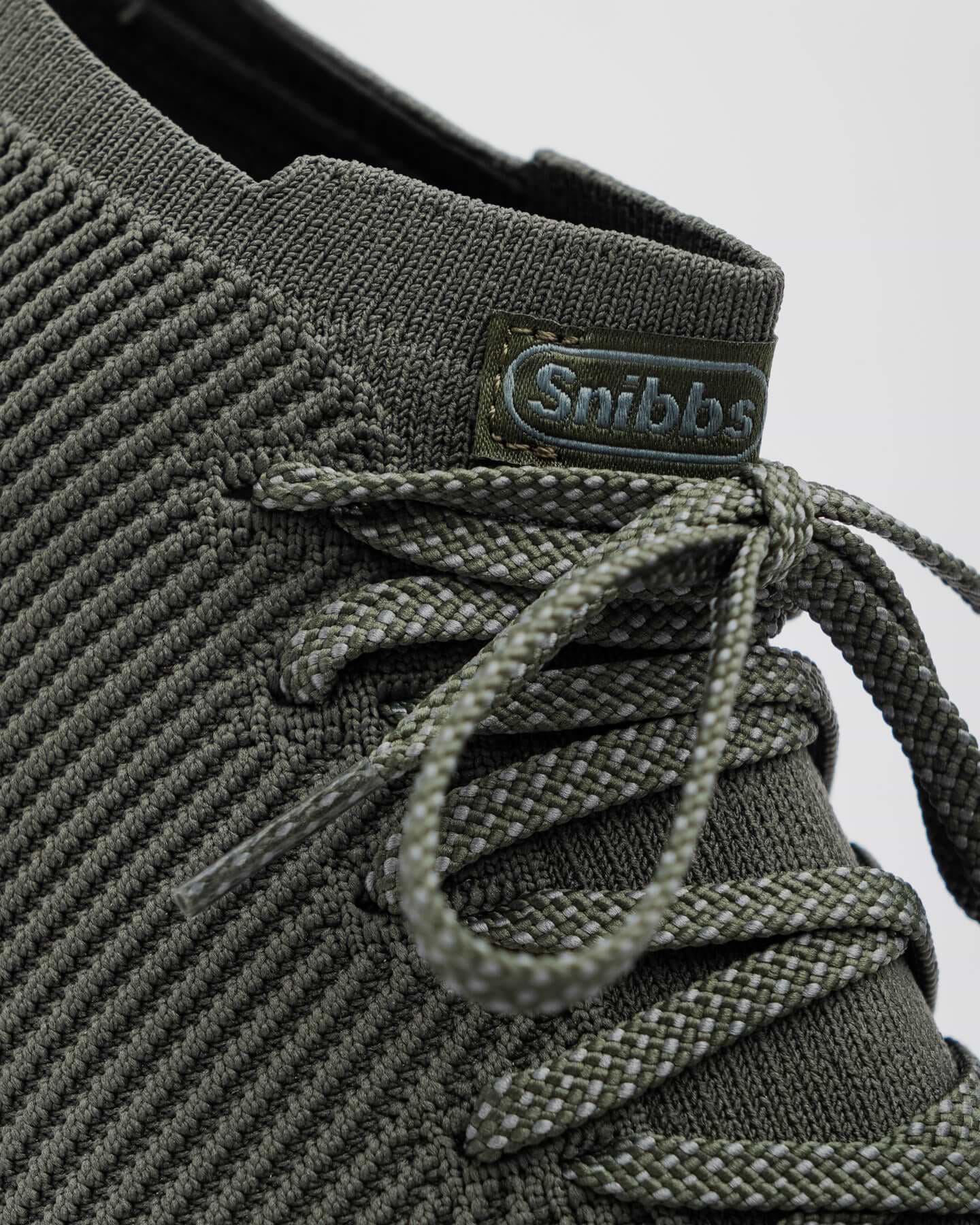 Close-up of the Snibbs ROVR Mid - Climbing Ivy sneaker with slip-resistant soles and a green "Snibbs" tag on the tongue.
