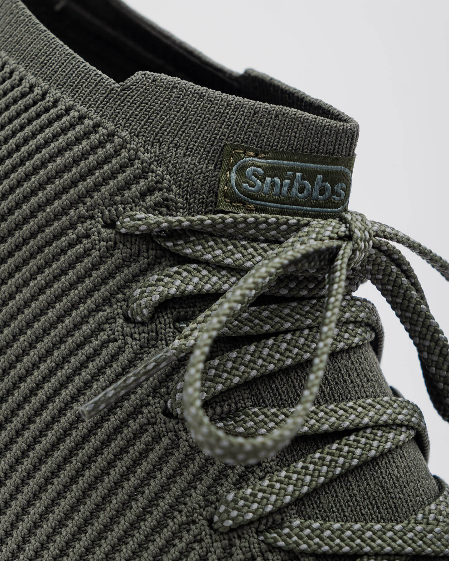 Close-up of the Snibbs ROVR Mid - Climbing Ivy sneaker with slip-resistant soles and a green "Snibbs" tag on the tongue.