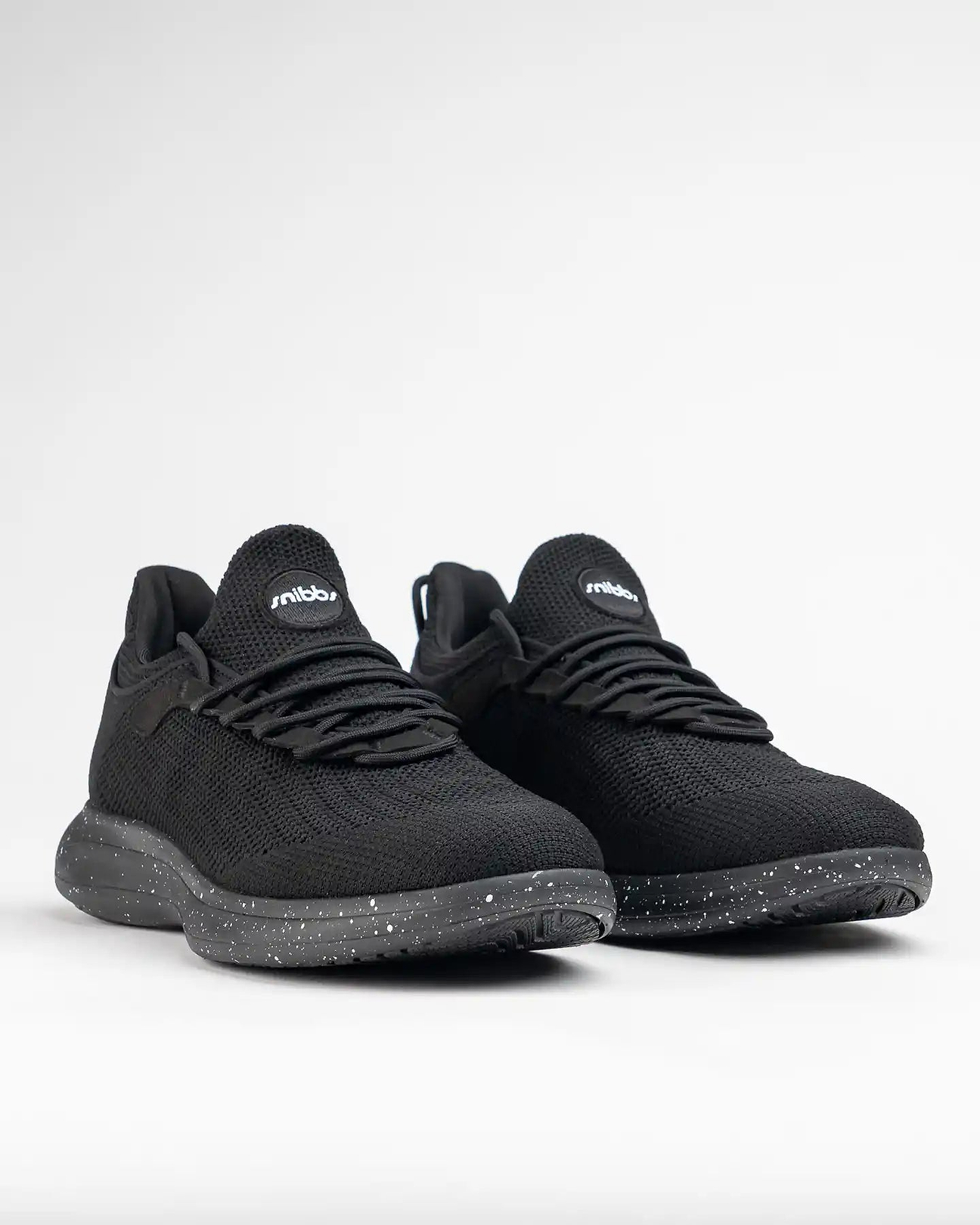 Black sneakers with speckled soles on a white background.