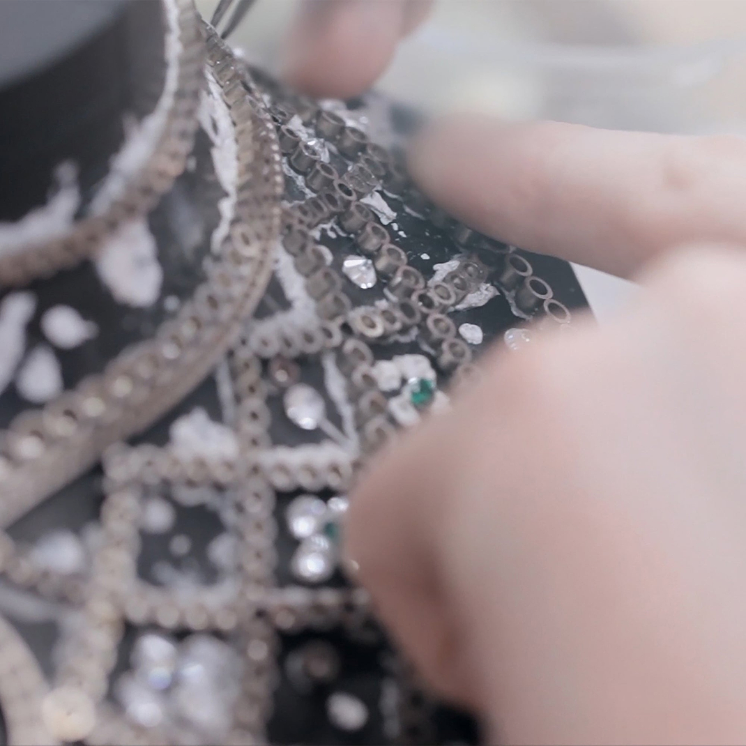 Macro close-up of the Fabergé Romanov necklace during production, showcasing intricate gemstone setting and handcrafted metalwork by a jeweller.