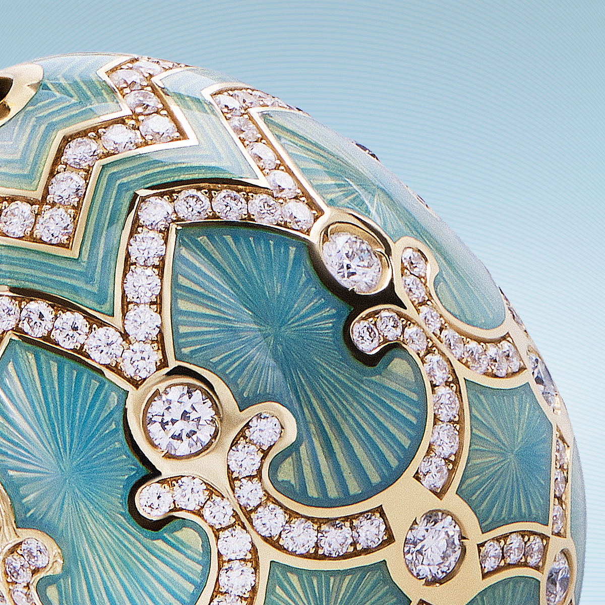 Close-up of a luxury Faberge turquoise guilloché enamel and diamond jewellery design in yellow gold, showcasing intricate craftsmanship and fine gemstone detailing.