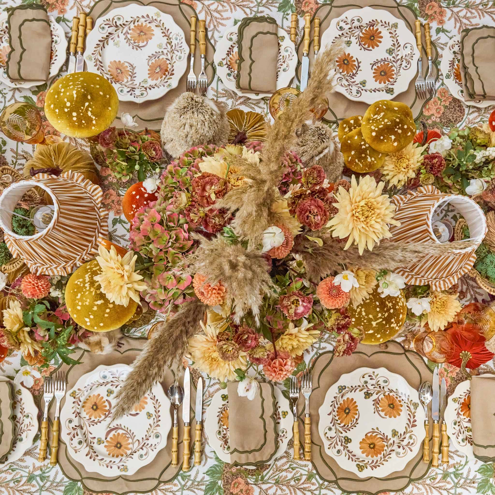 Colorful autumn-themed table setting with flowers, plates, and bamboo cutlery set.