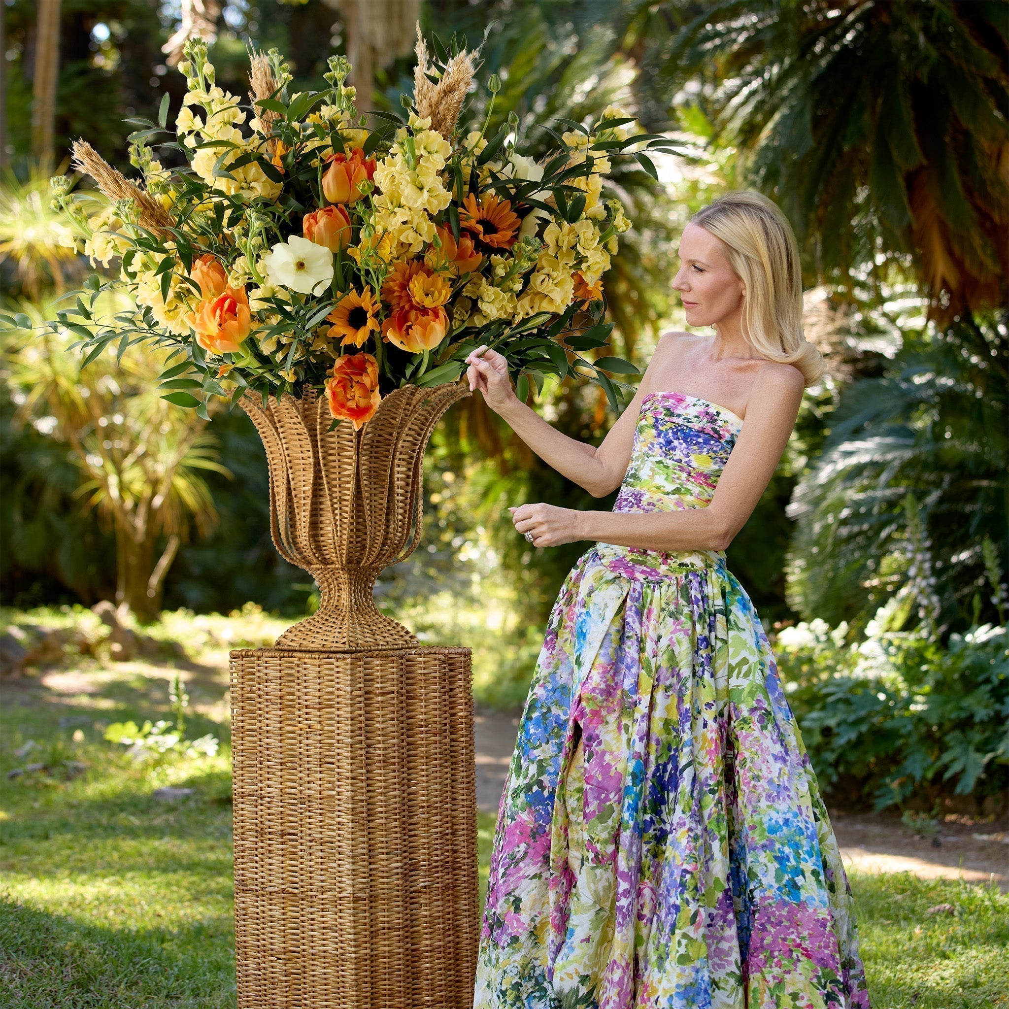 Premium Grade-A natural rattan column plinth and matching woven urn vase styled outdoors for an upscale garden gathering.