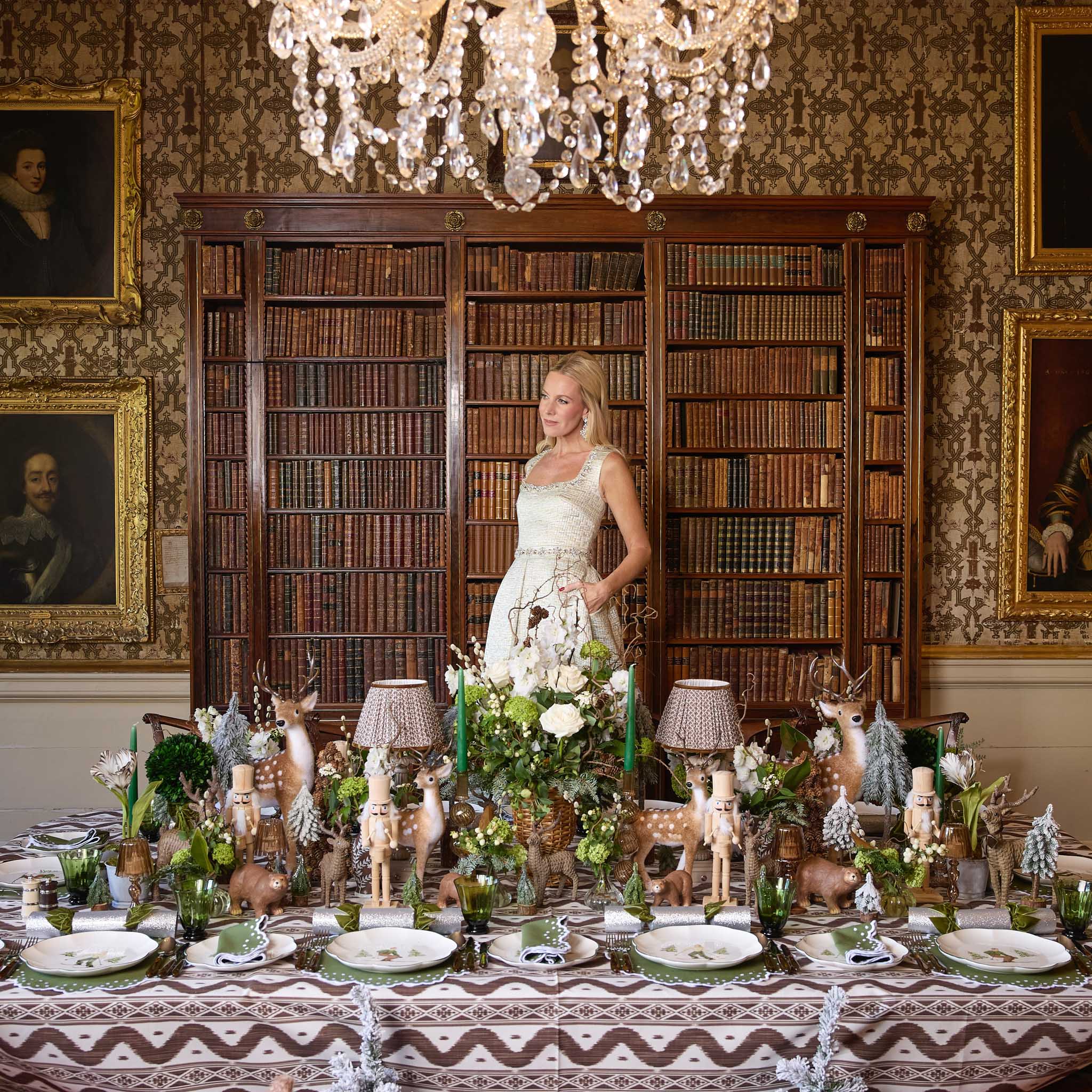 Woman in a white dress standing in an ornate room with a decorated table and bookshelf.