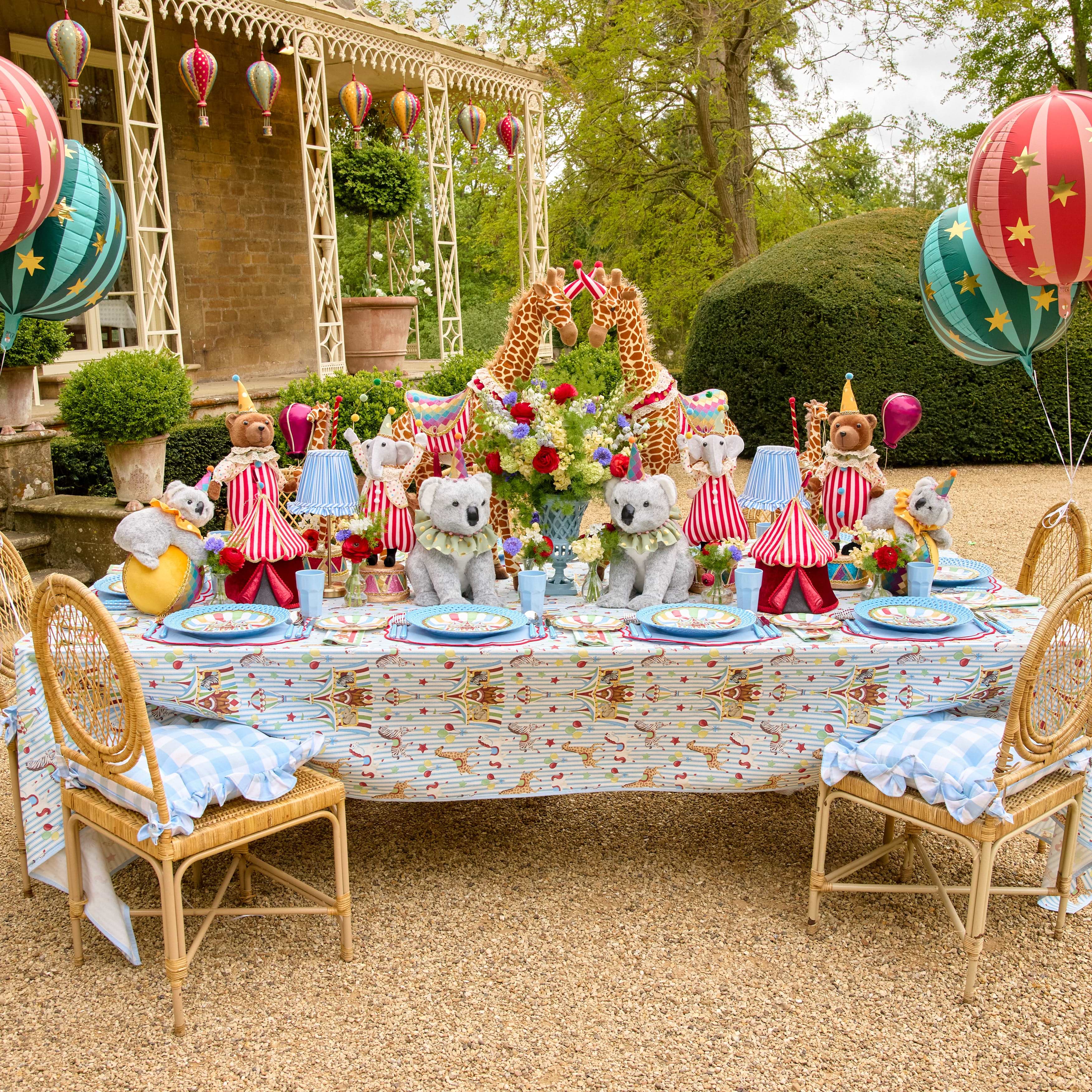 Decorative outdoor table setting with teddy bears, balloons, and a floral centerpiece.