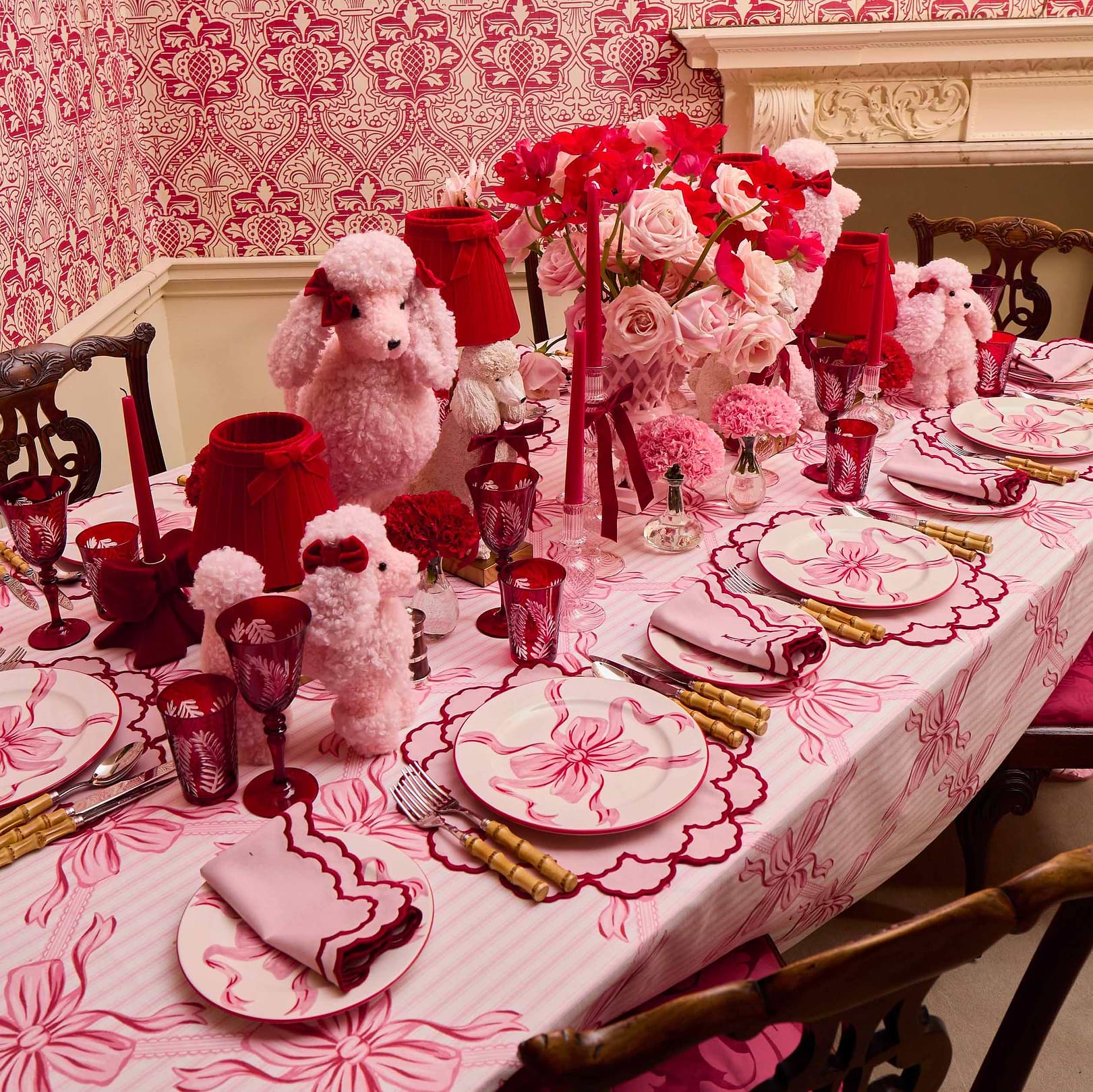 Decorative table setting with pink and red theme, including flowers and teddy bears.