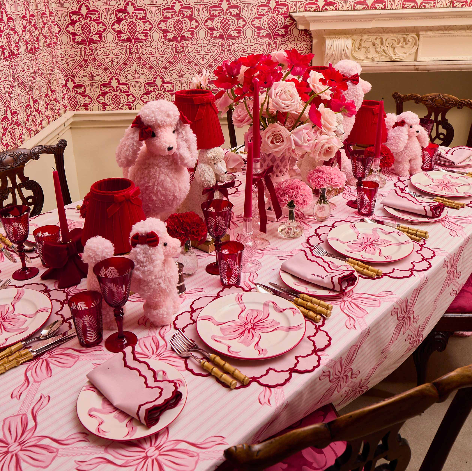 Decorative table setting with pink and red theme, including flowers and teddy bears.