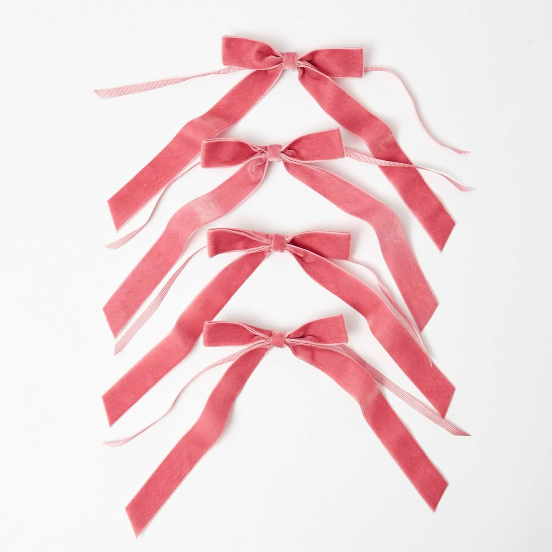 A set of four dusty pink velvet bows arranged on a white background.