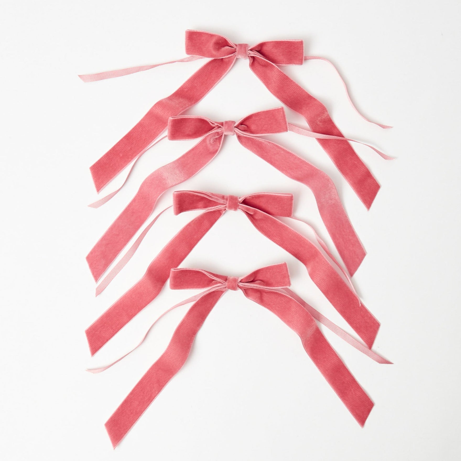 A set of four dusty pink velvet bows arranged on a white background.