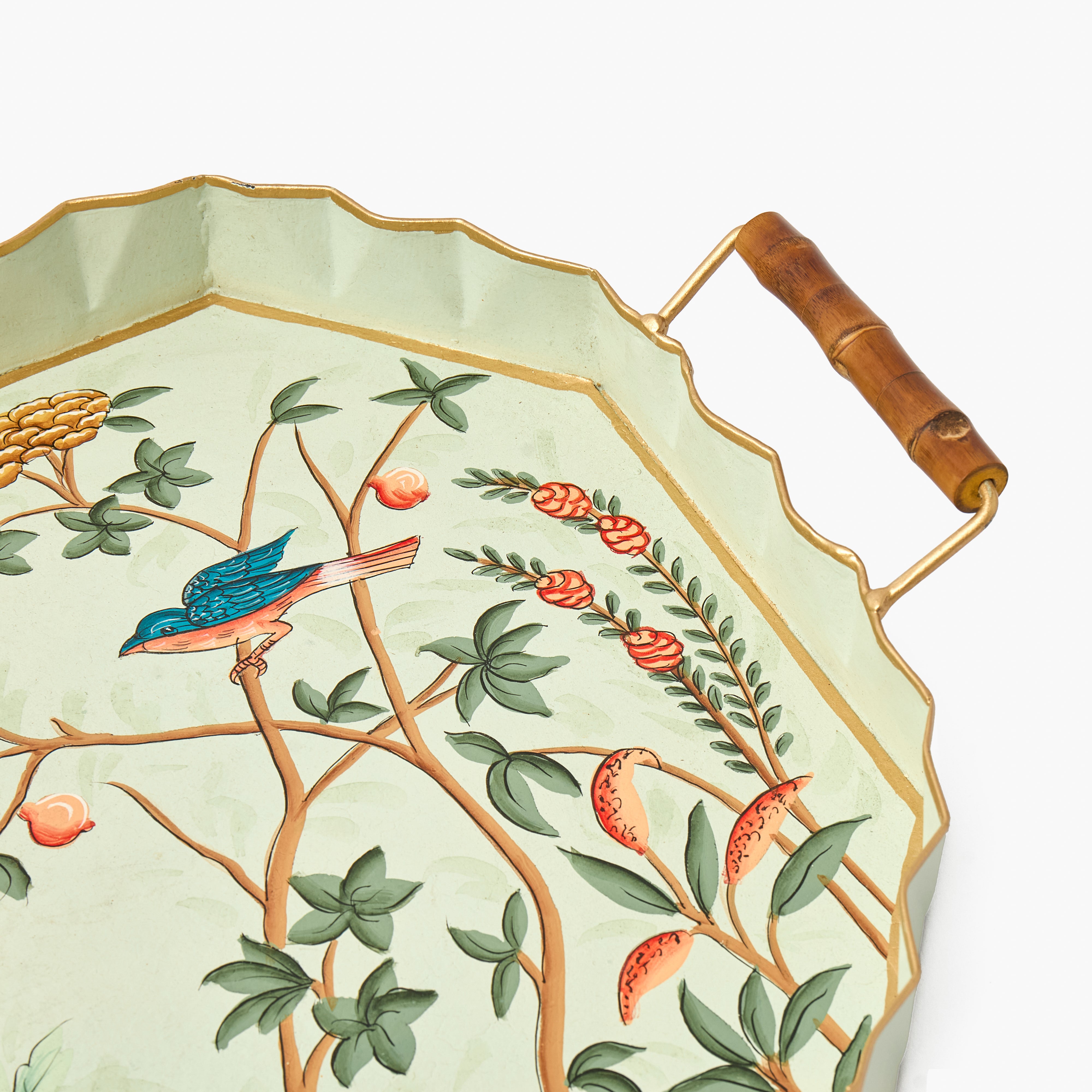 A decorative rectangular serving tray with scalloped edges, a bamboo-style handle, and a light green background printed with a bird and botanical motif in green, orange, blue, and gold tones.