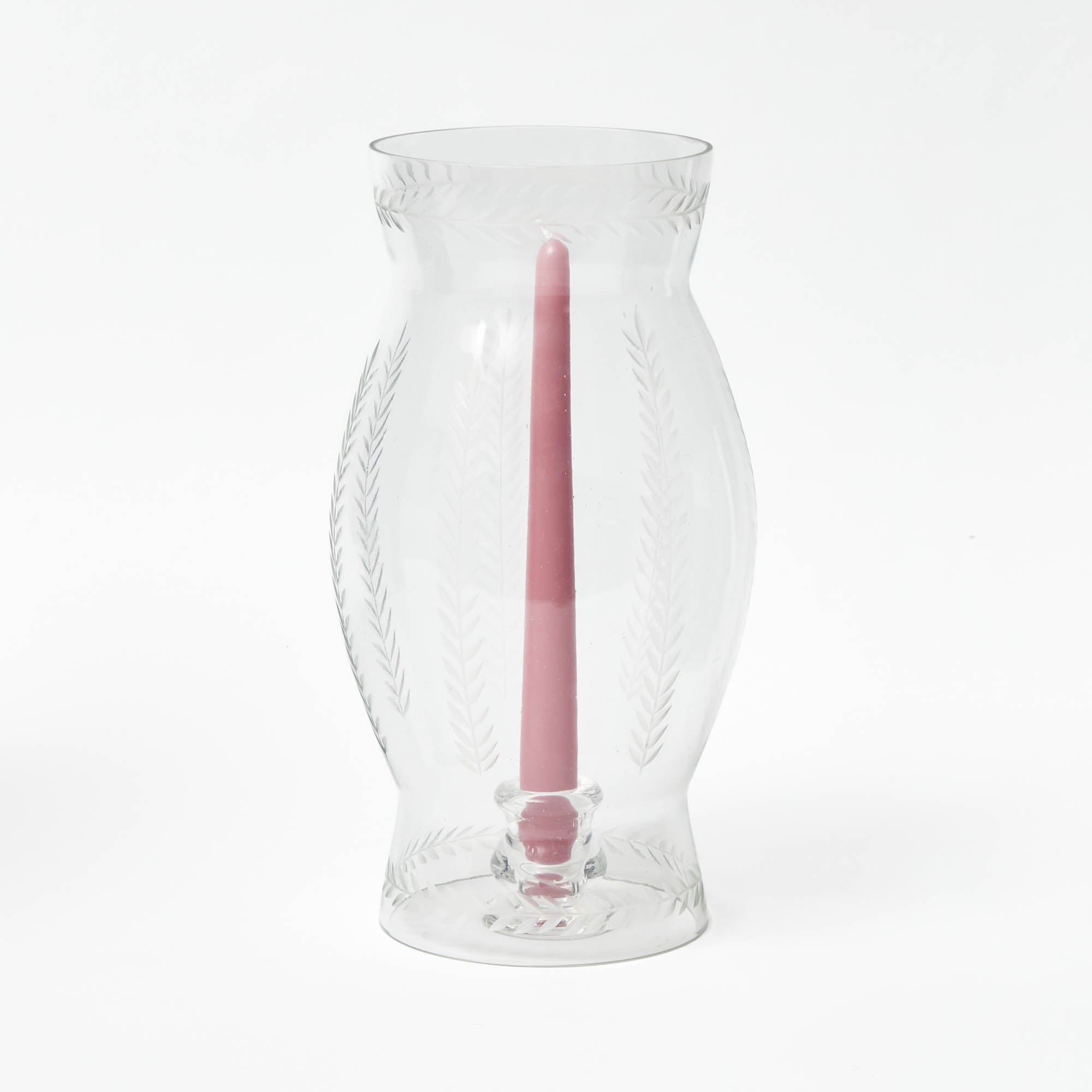 A clear glass lantern with engraved laurel leaf details, containing a pink candle.
