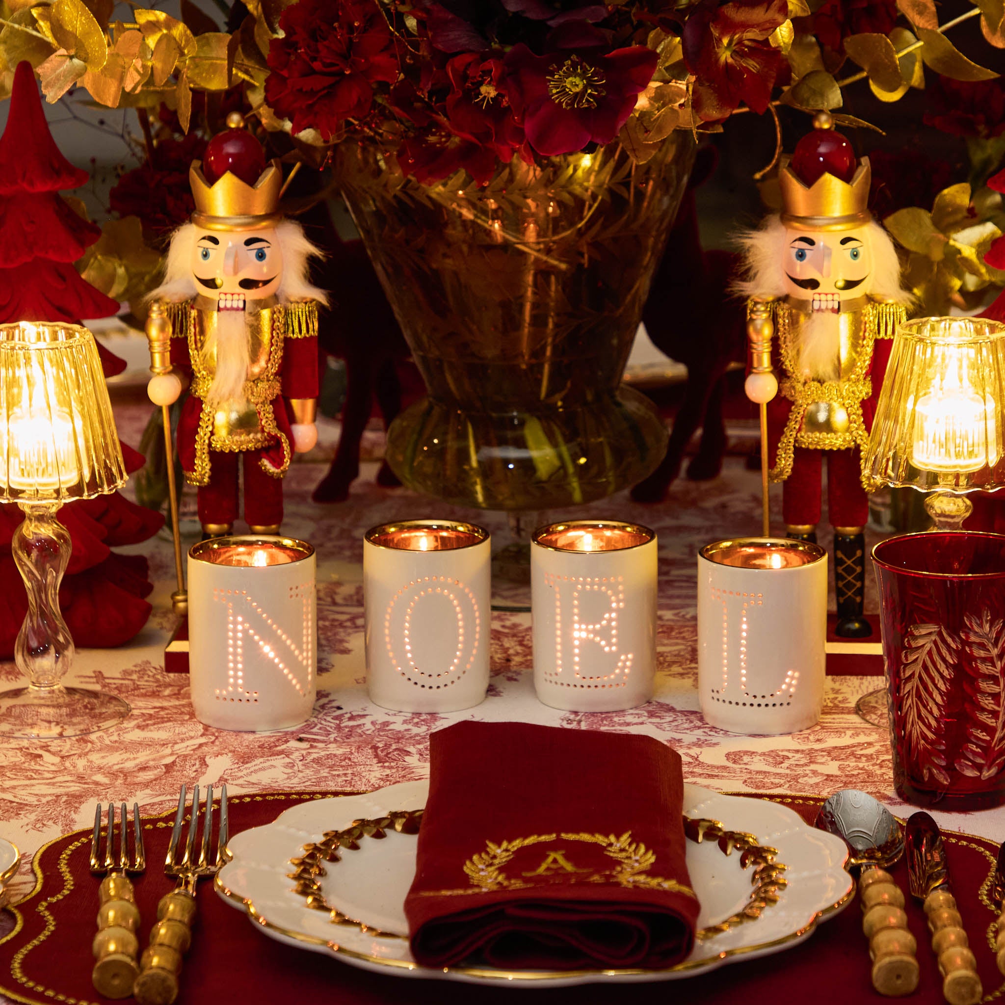 Decorative table setting with candles, nutcrackers, and floral arrangement.