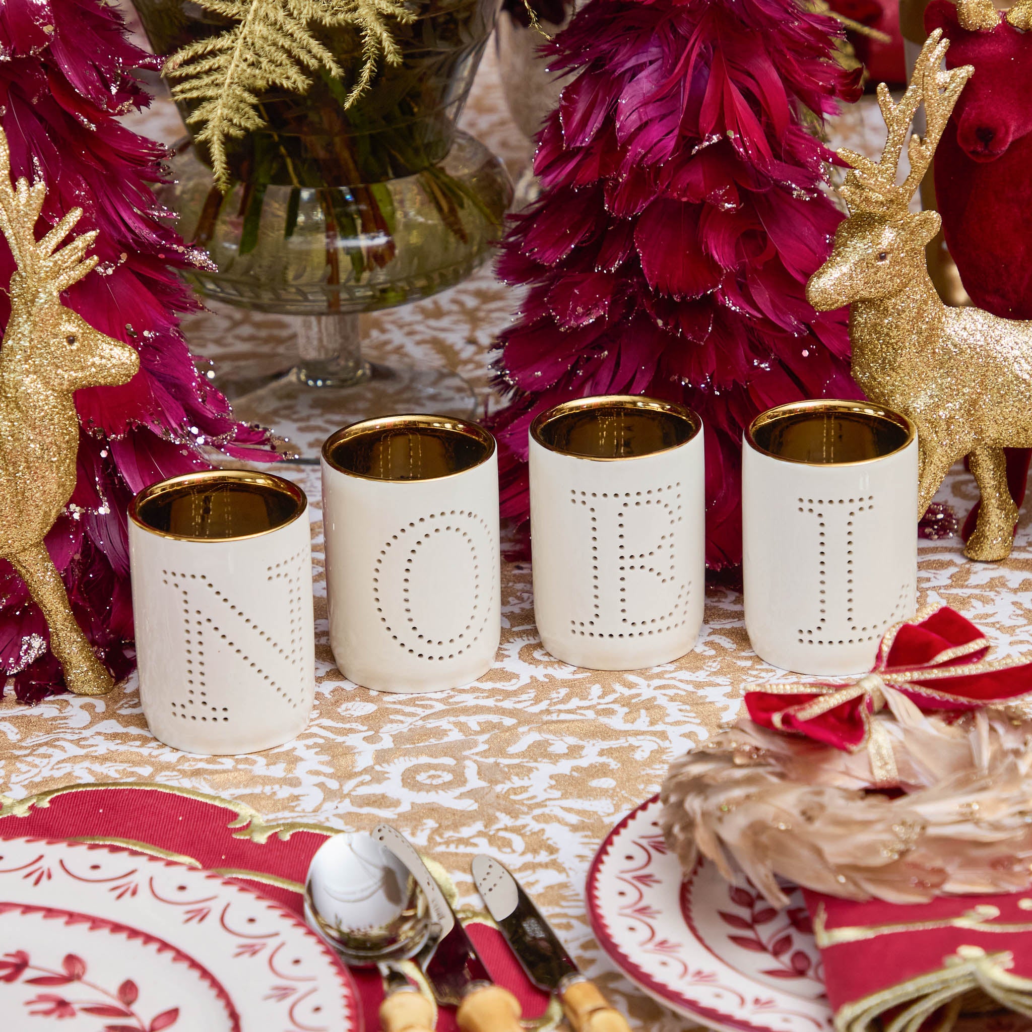 Decorative table setting with gold and red elements, including candles and reindeer figurines.