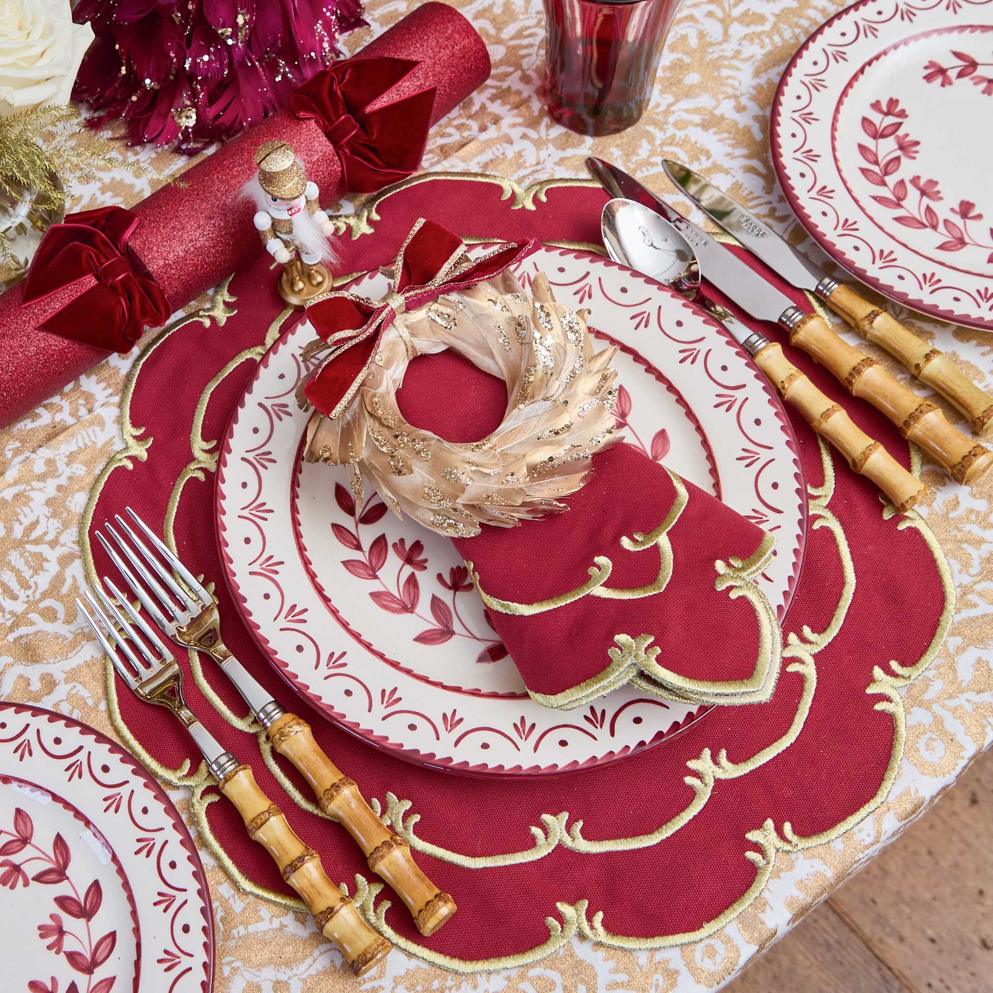 Decorative Christmas table setting with red and gold plates, napkins, and cutlery.