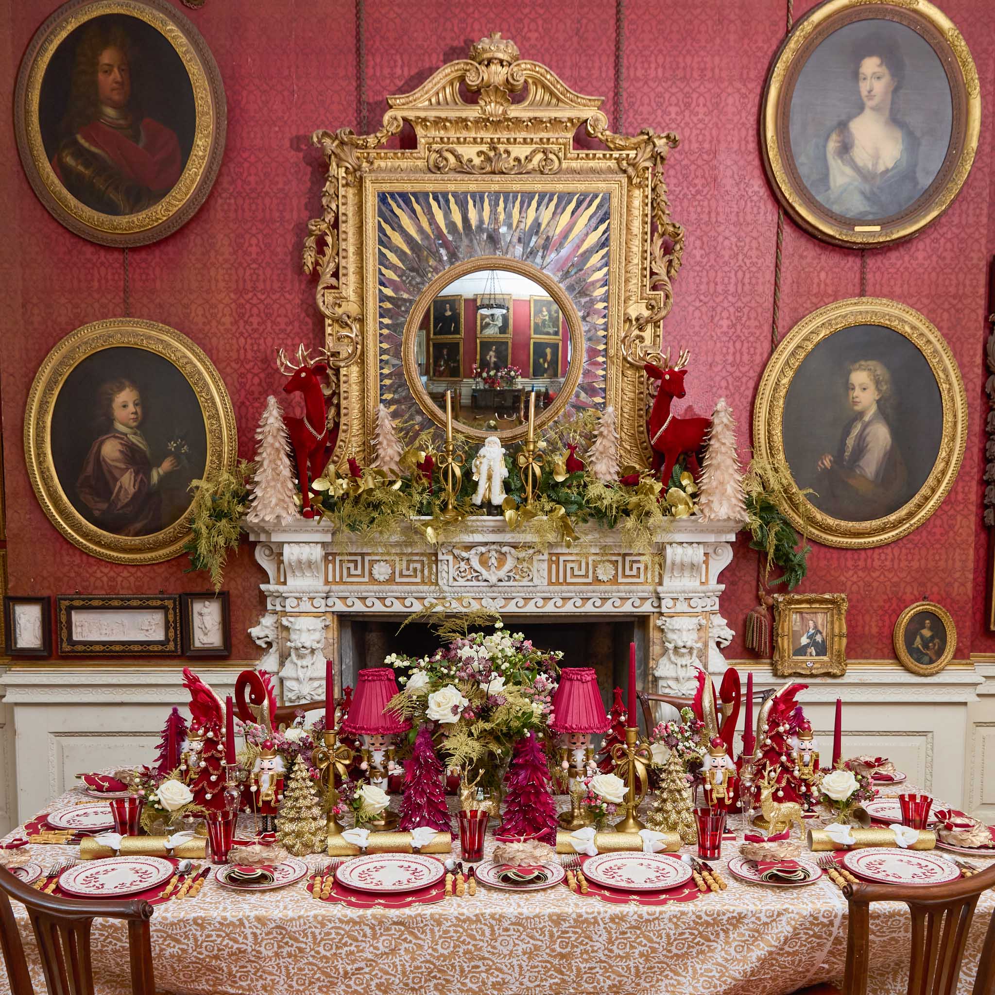 Decorative xmas table setting in a room with red walls, portraits, and a large mirror.