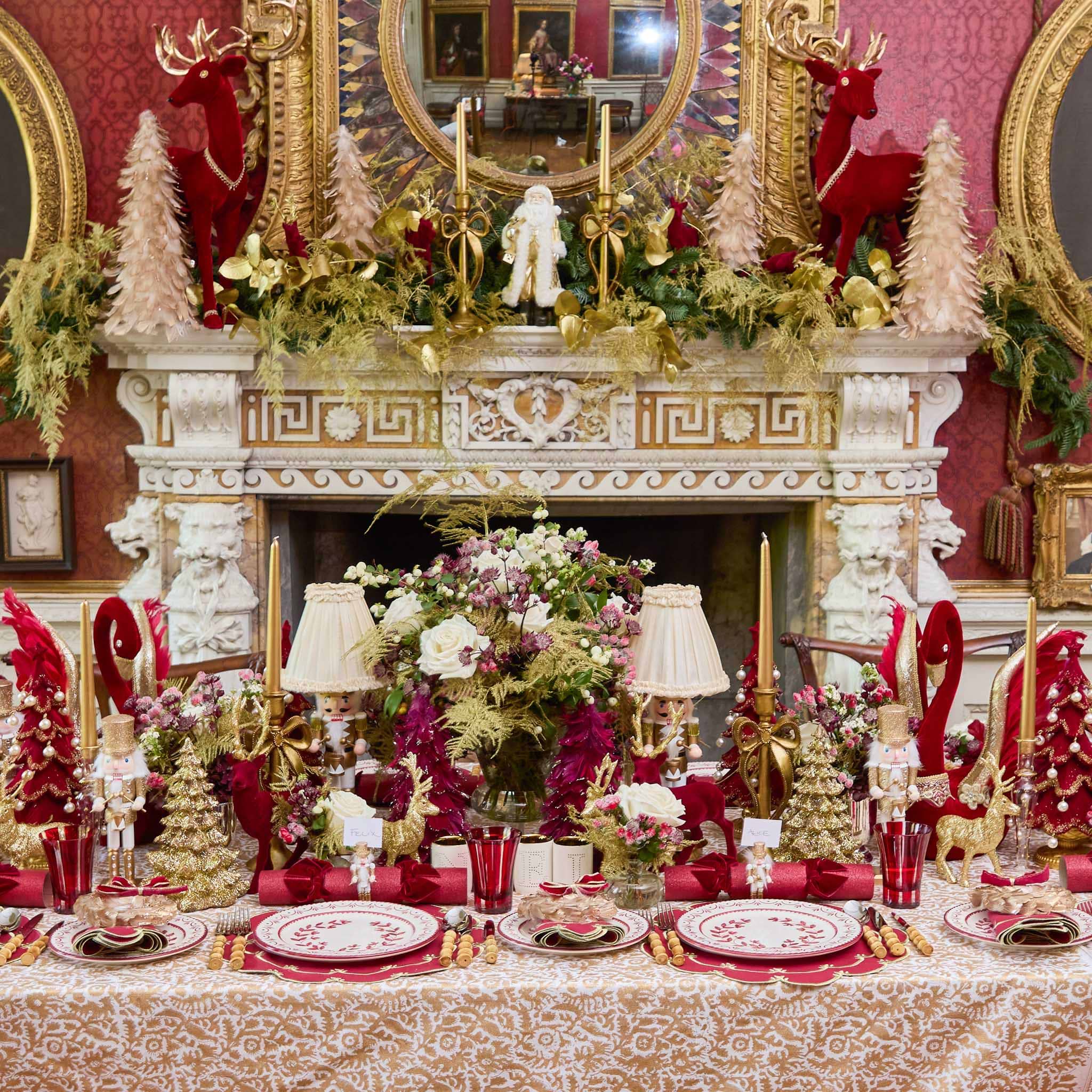 Decorative Christmas table setting with red and gold theme in a richly decorated room.