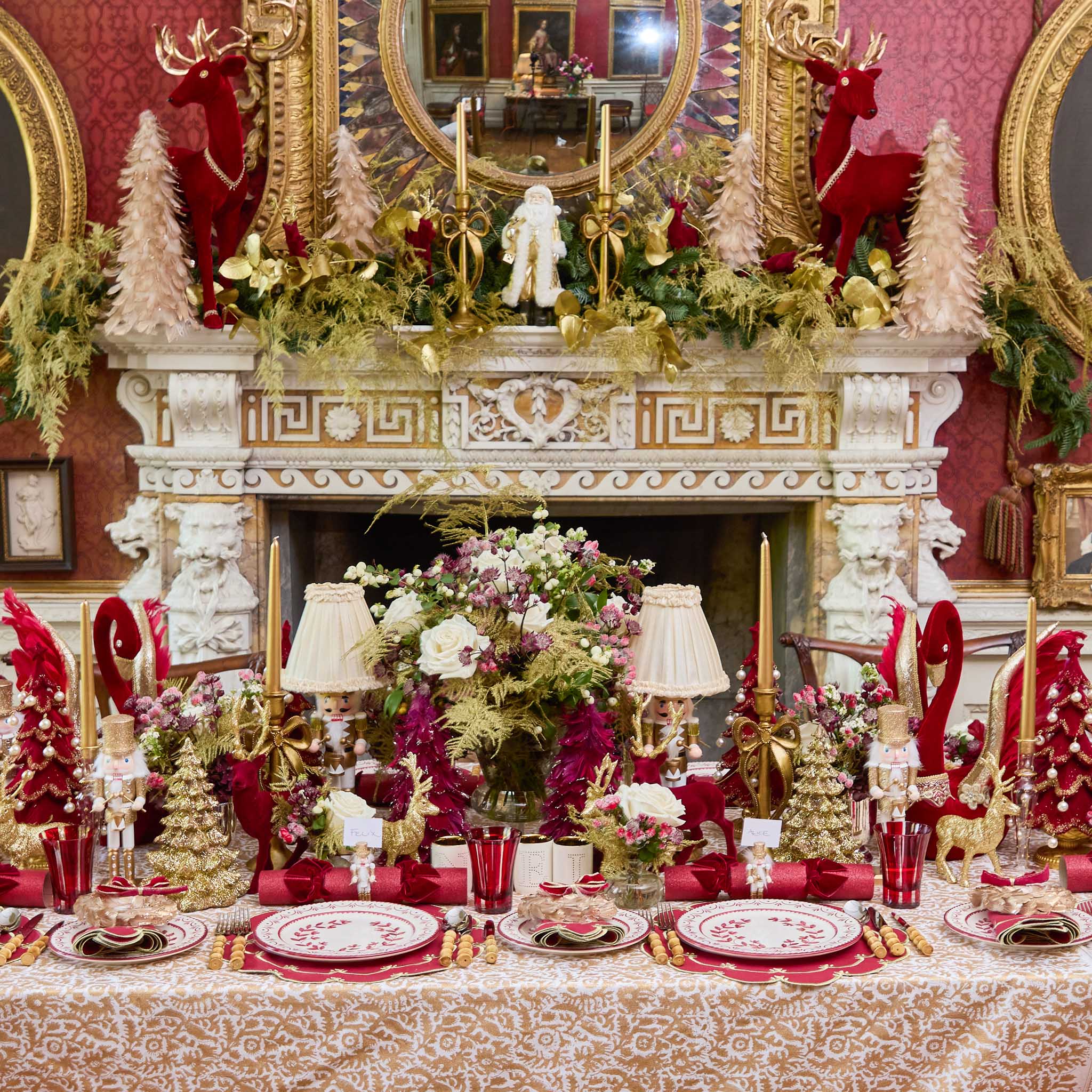 Decorative Christmas table setting with red and gold theme in a richly decorated room.