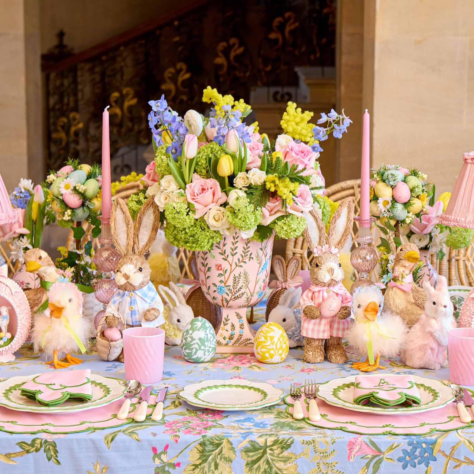 Easter-themed table setting with floral arrangements, bunny figurines, and pastel colors.