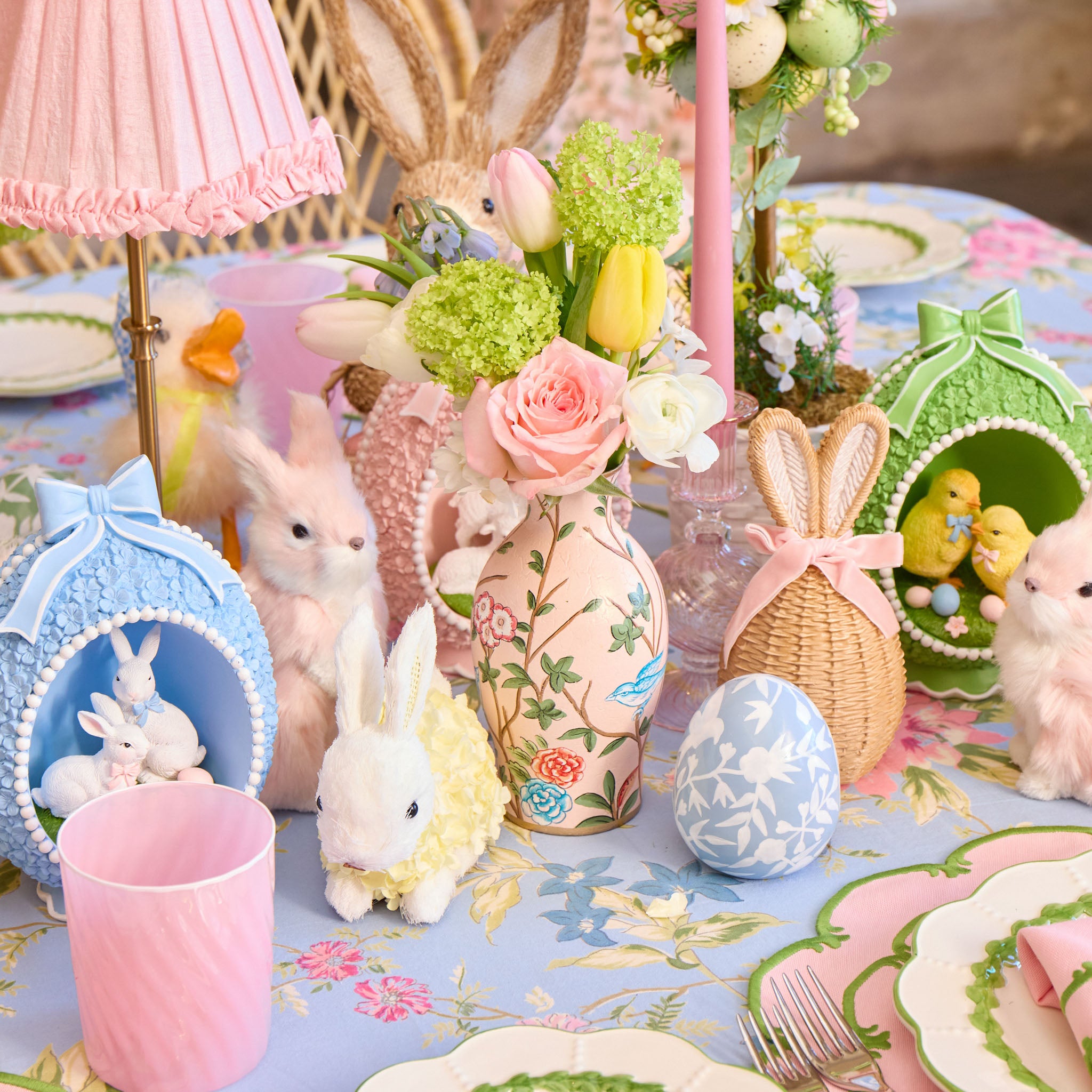Easter-themed table setting with decorative items, including bunny figurines and floral arrangements.