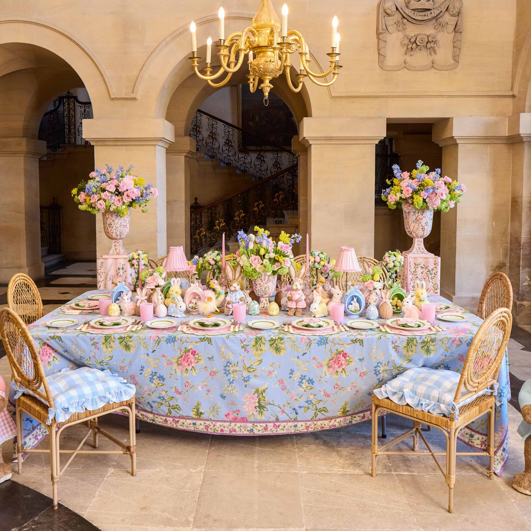 Decorative table setting with floral tablecloth and centerpieces in a grand room.