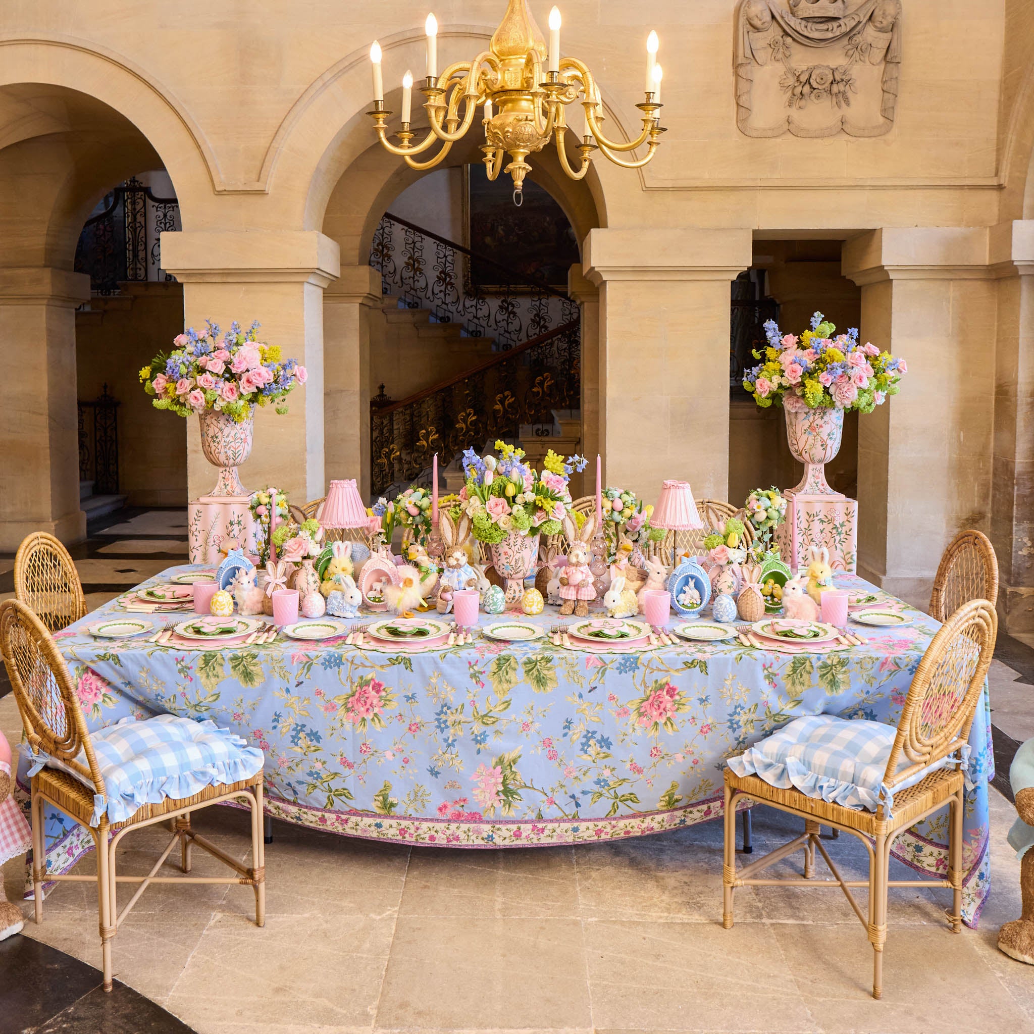Decorative table setting with floral tablecloth and centerpieces in a grand room.