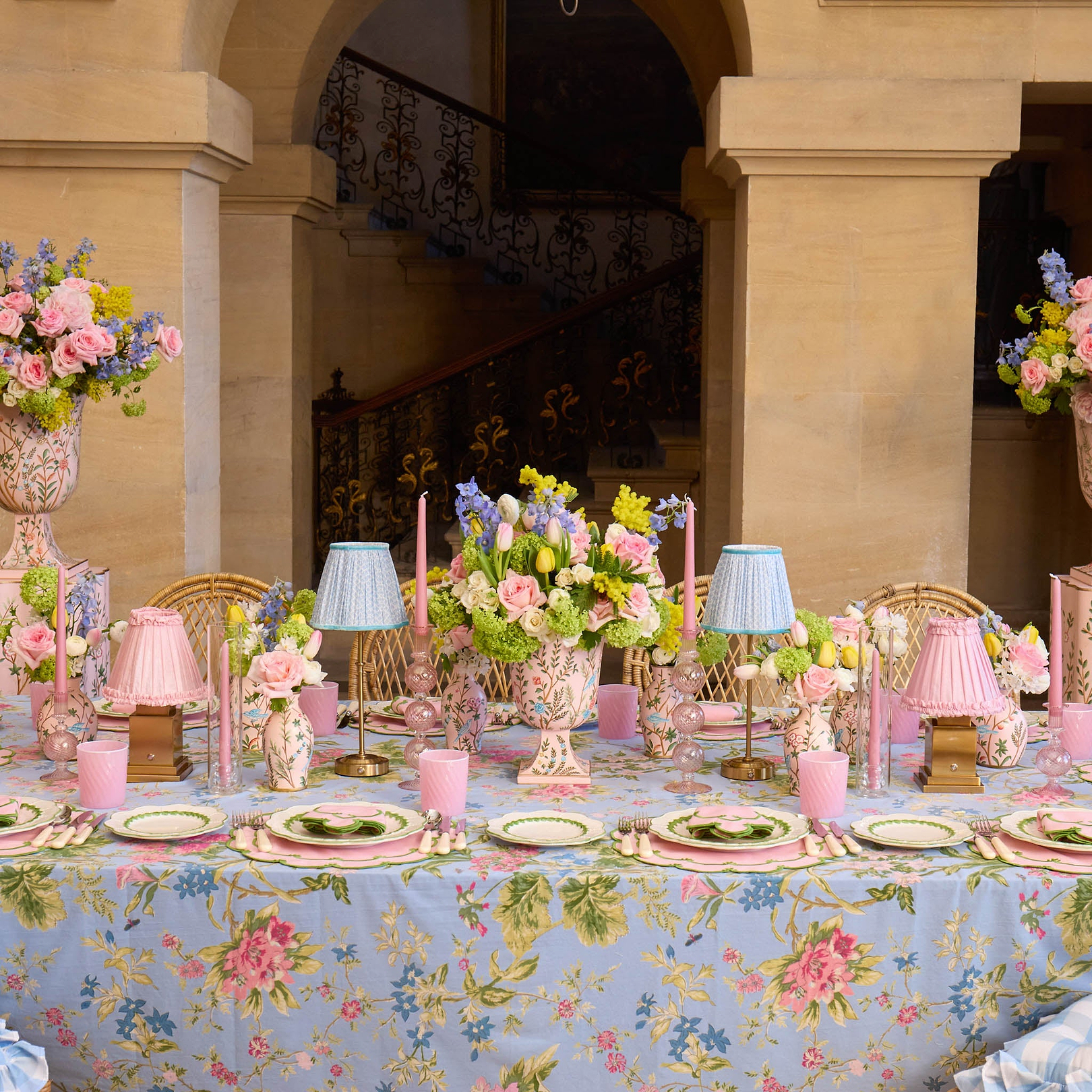 Decorative table setting with floral centerpieces, candles, and tablecloth in an elegant indoor setting.