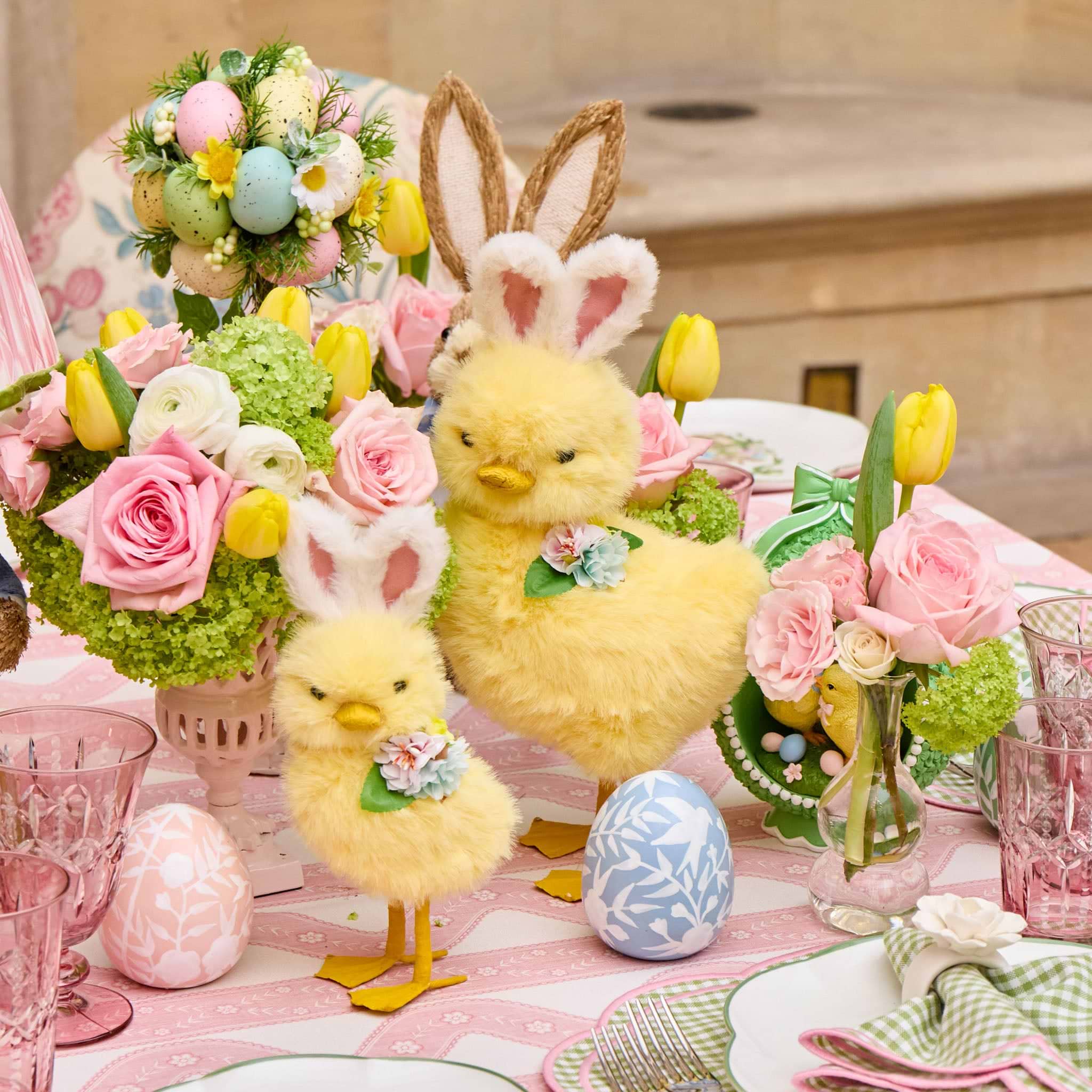 Decorative Easter table setting with yellow chicks, floral arrangements, and Easter eggs.