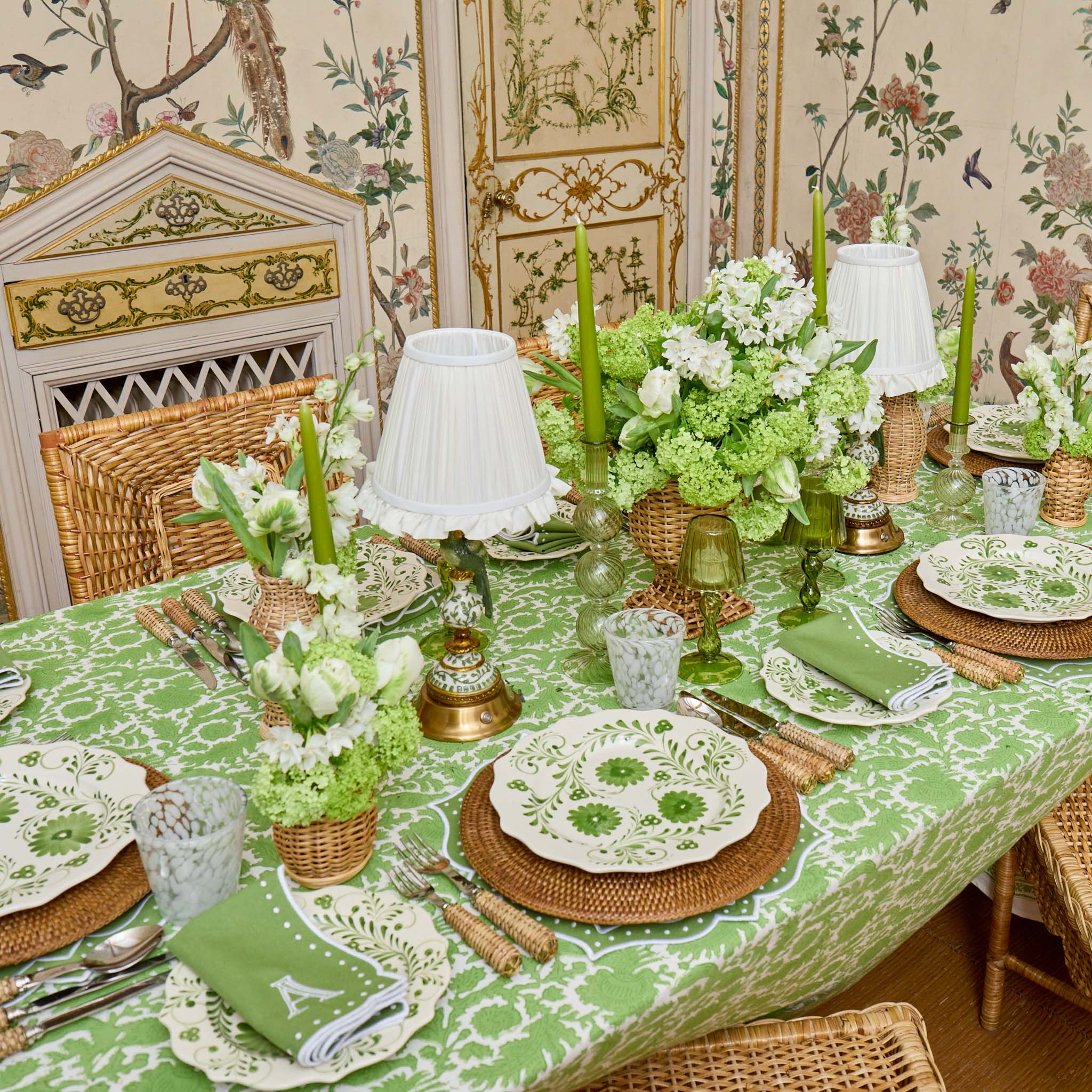 Decorative table setting with green and white theme in a room with floral wallpaper.