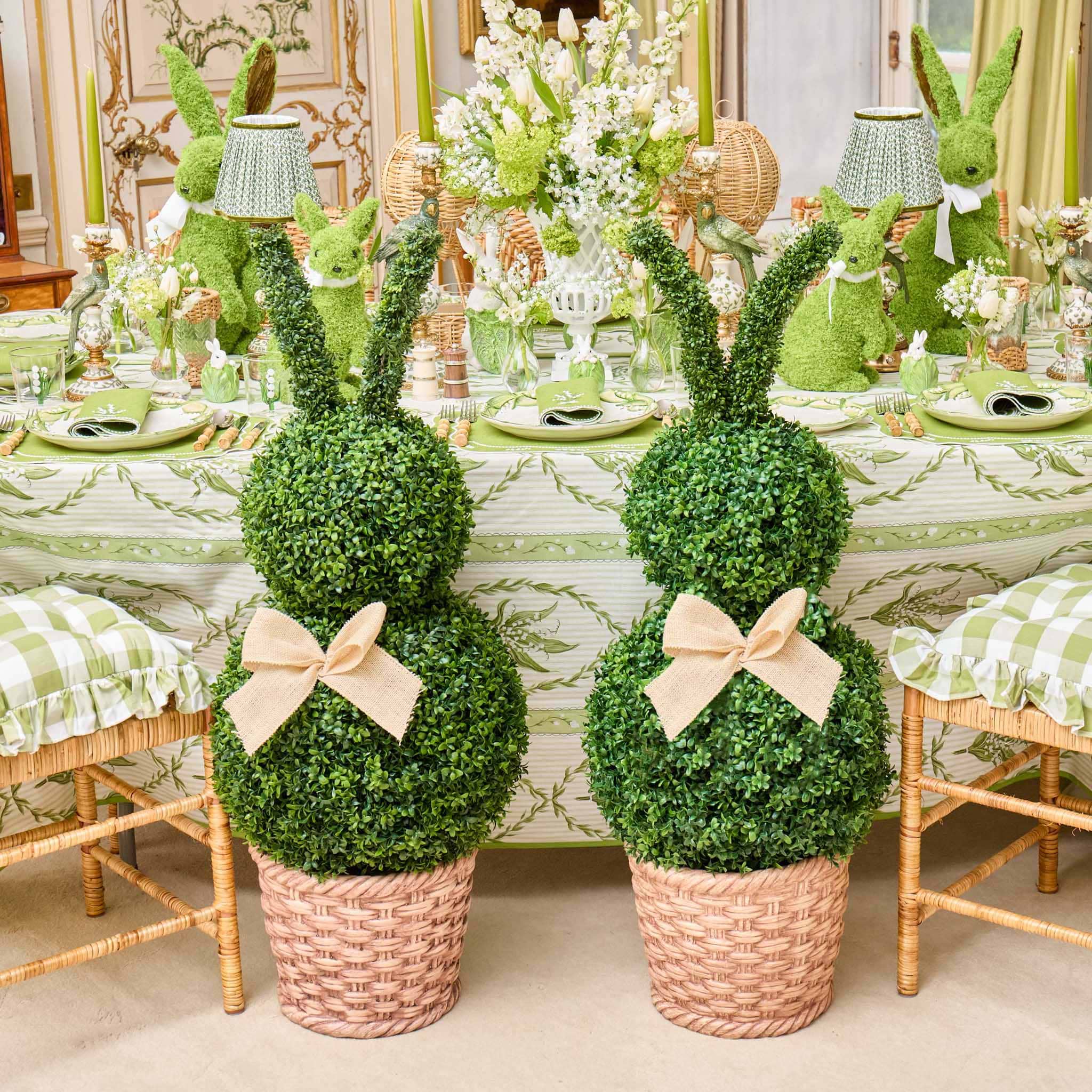 Decorative topiary rabbits with greenery on a table setting.
